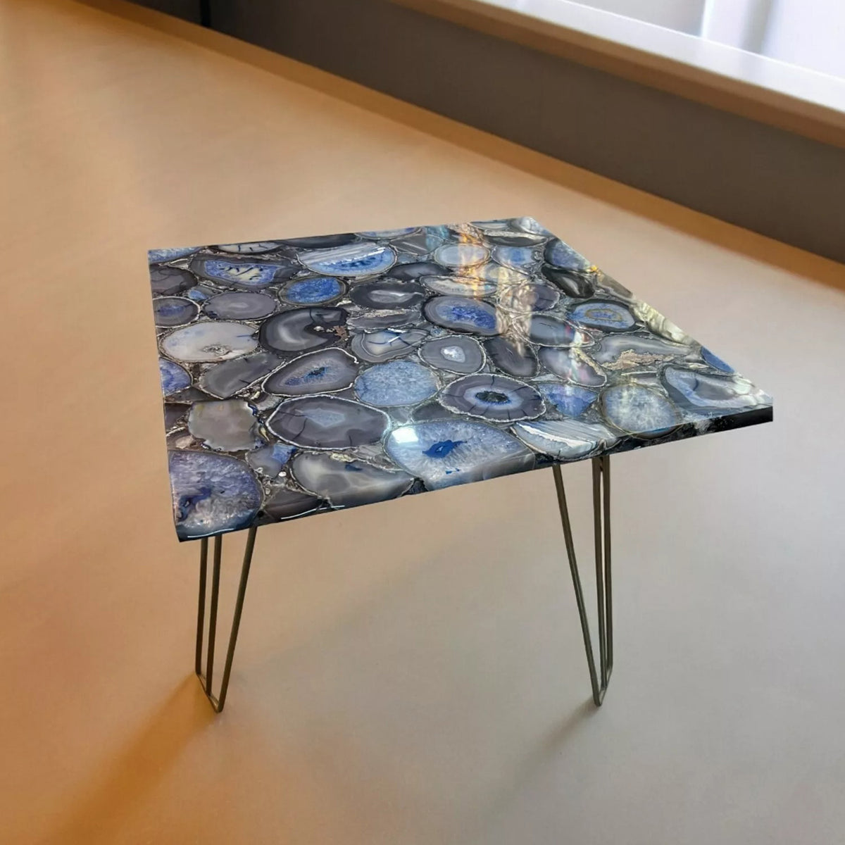 A rectangular blue Brazil agate stone table top displayed on a metal tripod stand, showcasing its natural stone patterns.
