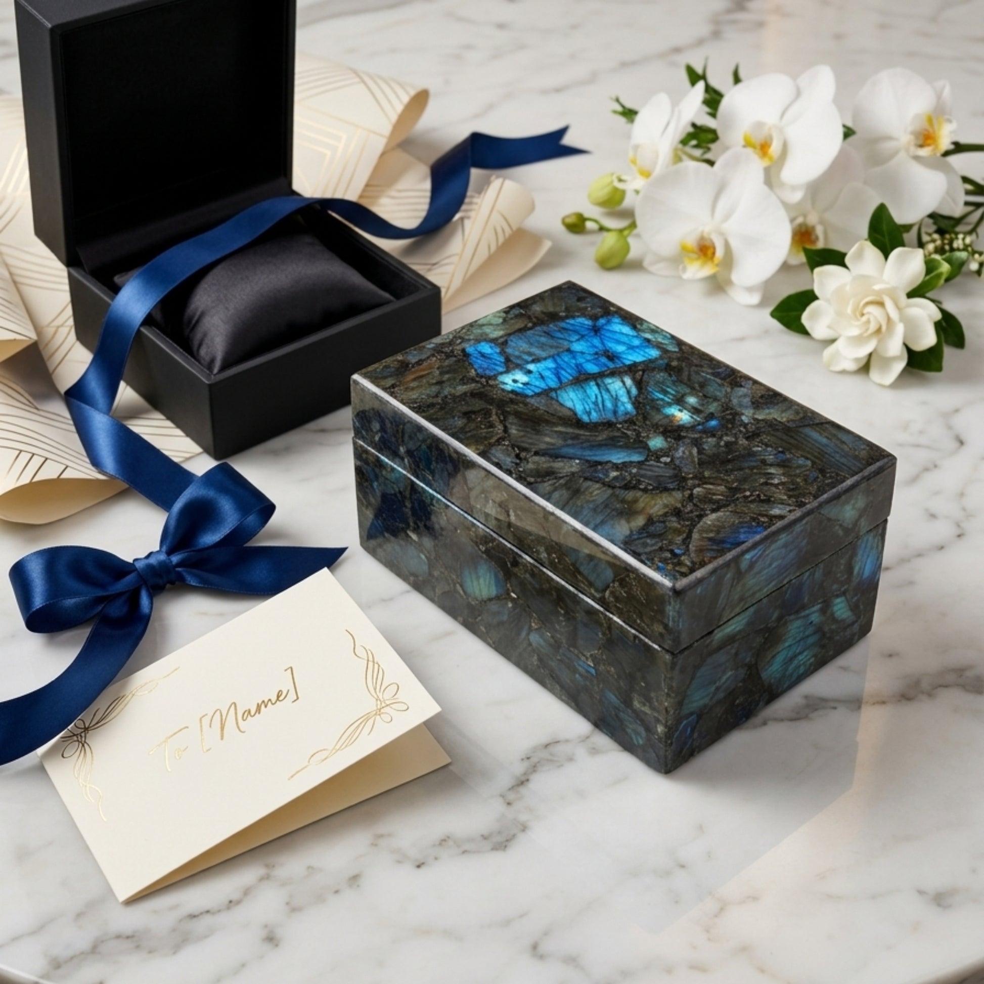 Luxury Handmade Labradorite Jewelry Box with gift box, blue ribbon, greeting card and white orchids on marble table by The Regal Art