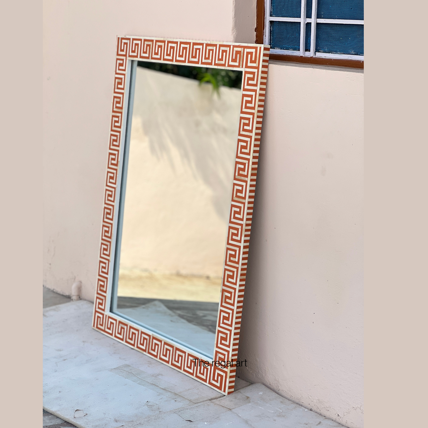 Decorative mirror with a geometric pattern on a white wall.