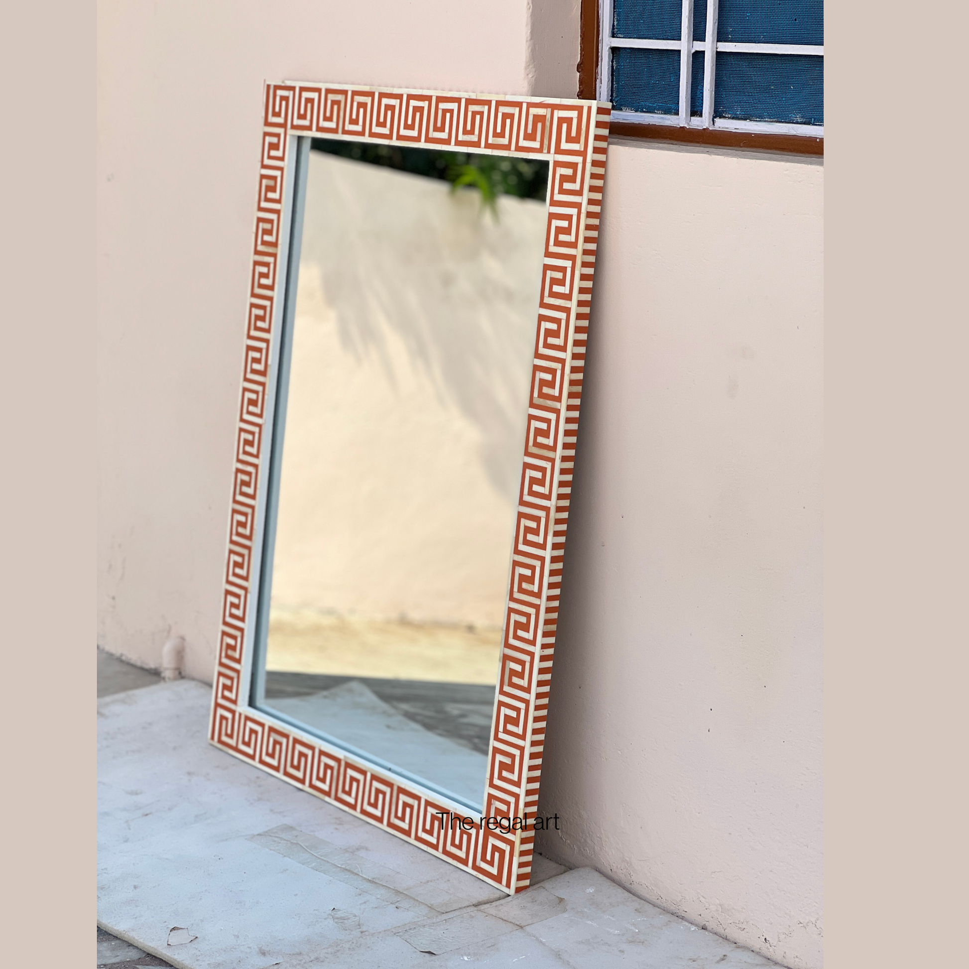 Decorative mirror with a geometric pattern on a white wall.