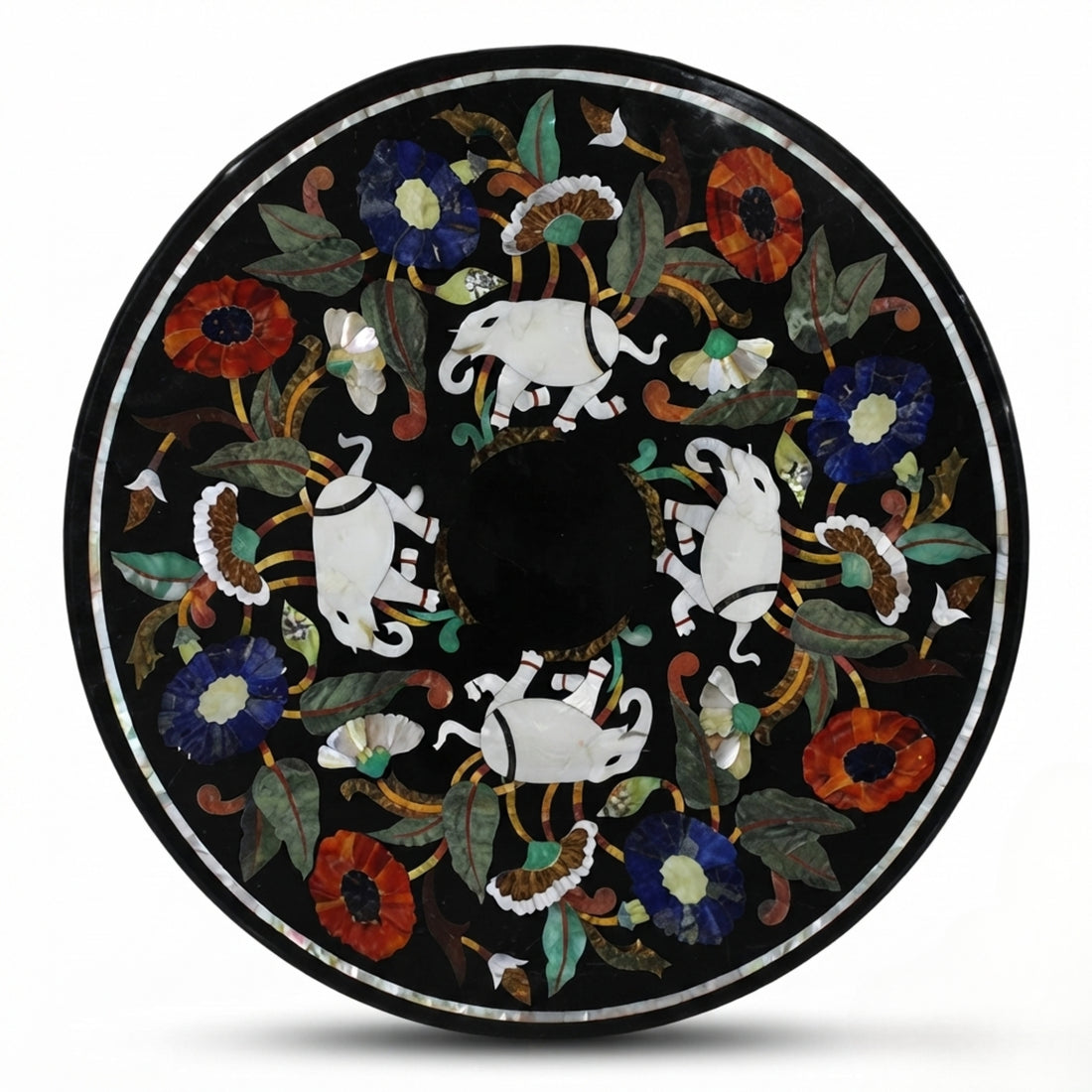 Handcrafted black marble round dining table with elephant and floral Pietra Dura inlay, styled in a modern luxury dining room with upholstered chairs.