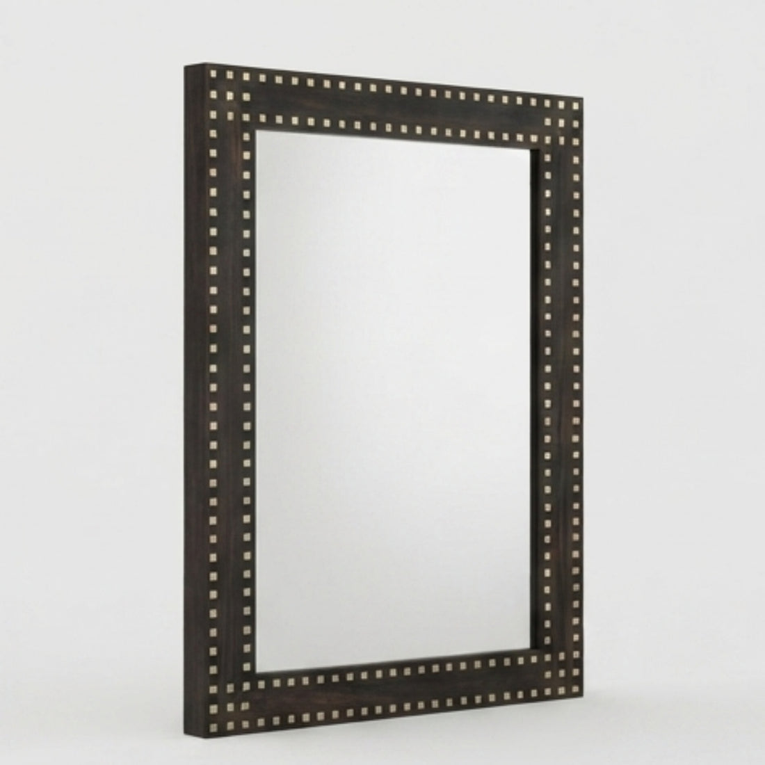A large rectangular wall mirror with a dark wood frame and silver nailhead trim hangs above a dark wood console table in a styled interior setting.