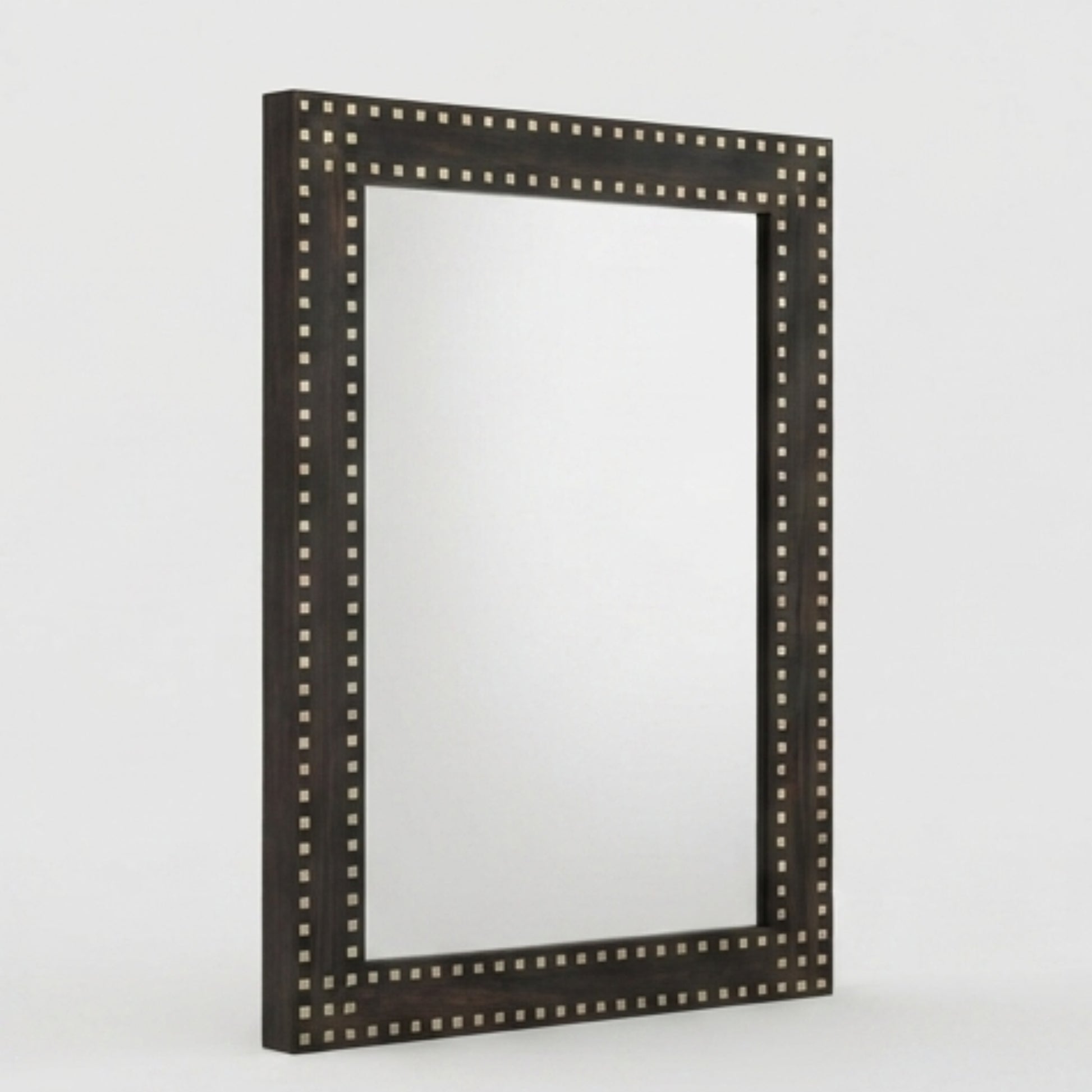 A rectangular wall mirror with a dark brown wooden frame adorned with small metallic studs, shown against a light gray background.