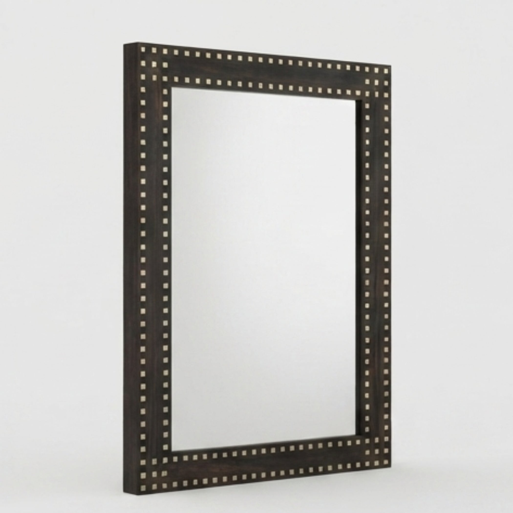 A rectangular wall mirror with a dark brown wooden frame adorned with small metallic studs, shown against a light gray background.