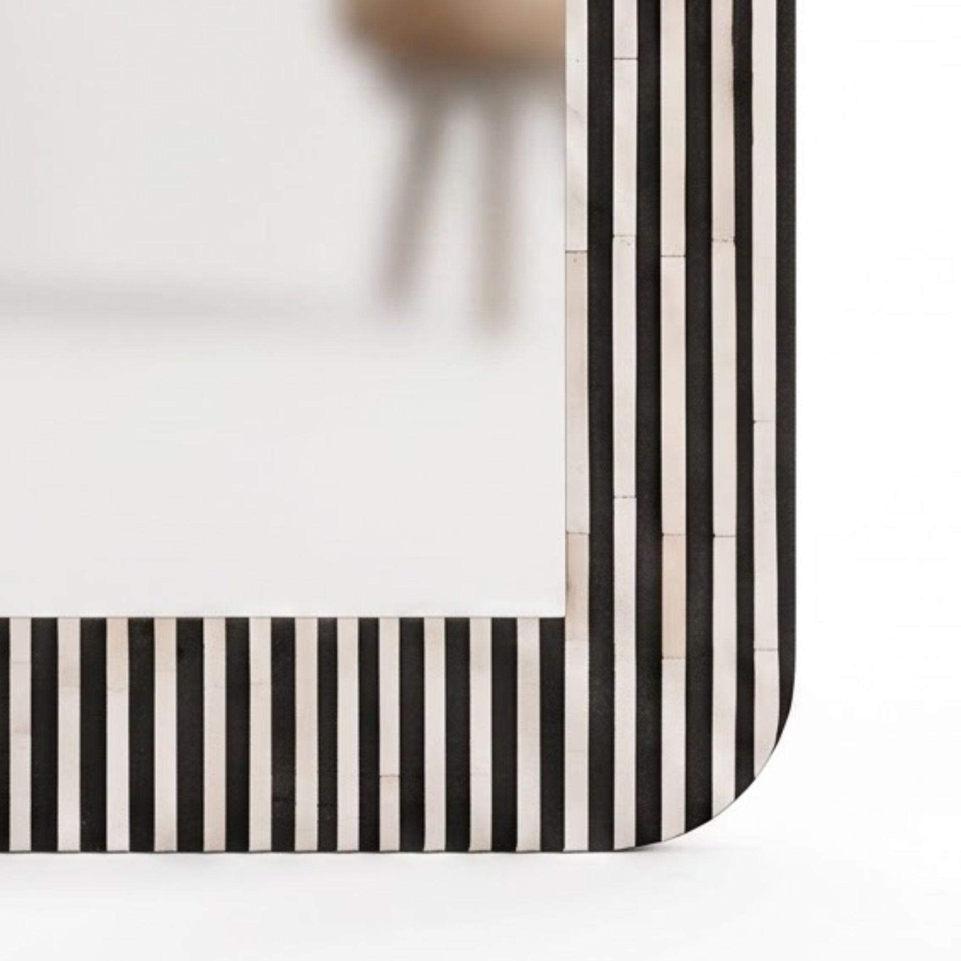 Close-up of a rectangular frame corner with narrow vertical black and off-white stripes, shown against a clean white background.
