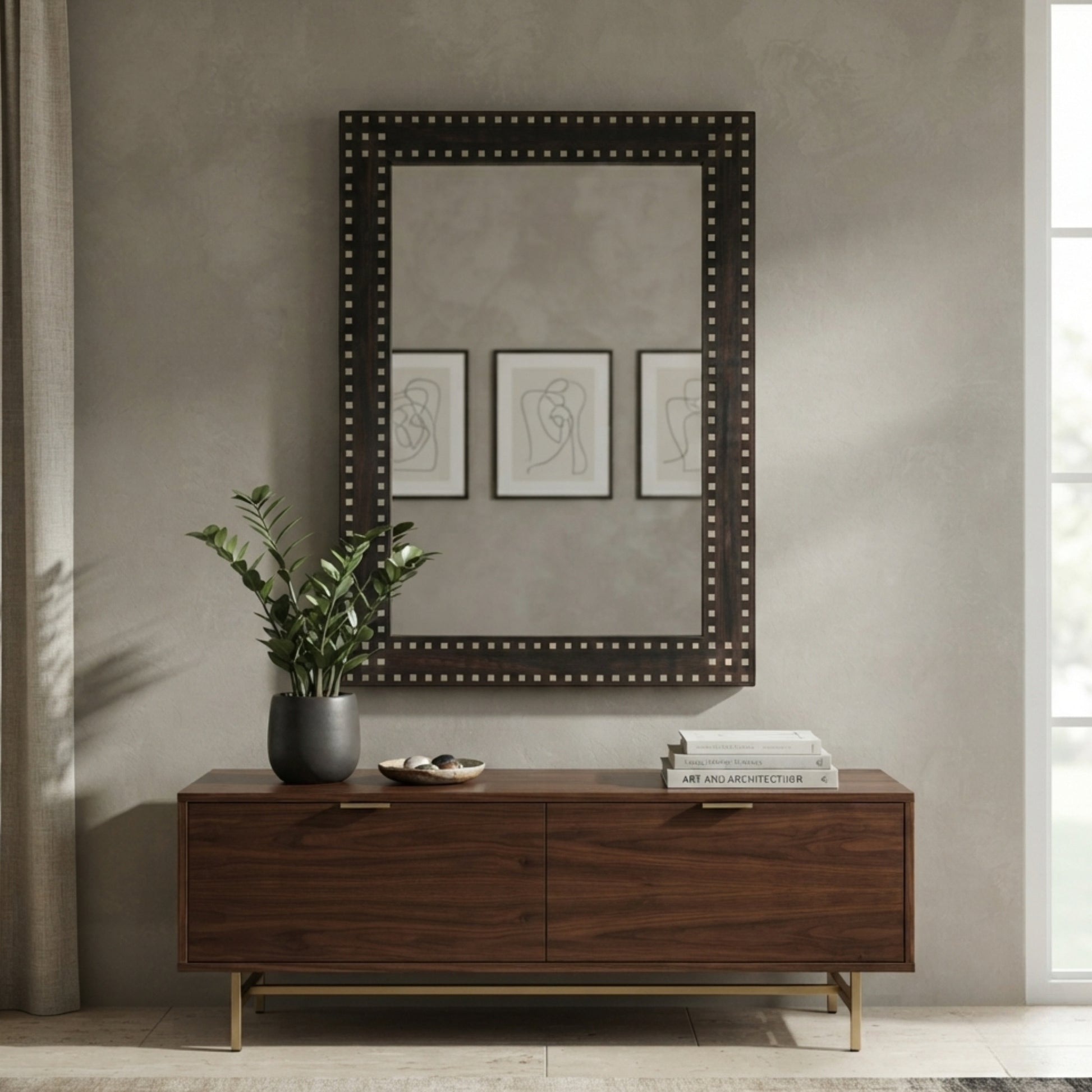 A large rectangular wall mirror with a dark wood frame and silver nailhead trim hangs above a dark wood console table in a styled interior setting.