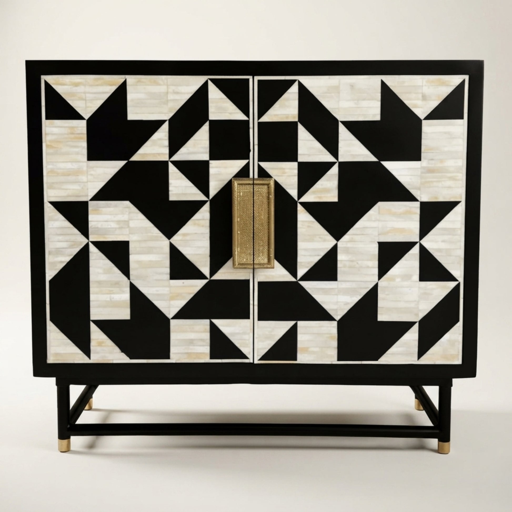 A two-door cabinet featuring a bold black and off-white geometric inlay pattern on the doors, with a central brass pull handle and a black frame supported by angled legs with brass tips, set against a plain light background.