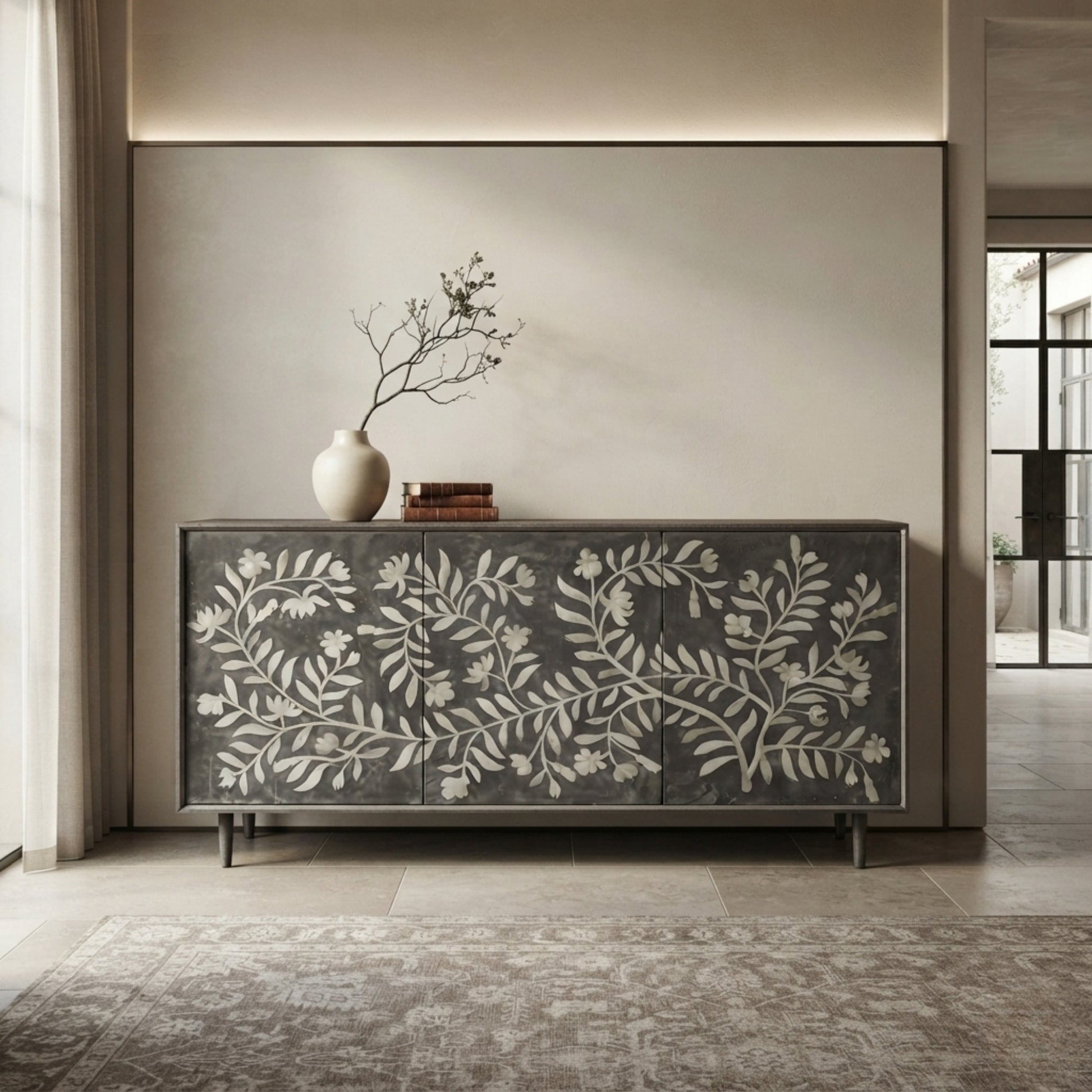 A dark gray sideboard cabinet with a white floral branch pattern on the front, styled in a modern interior with a vase and books on top.