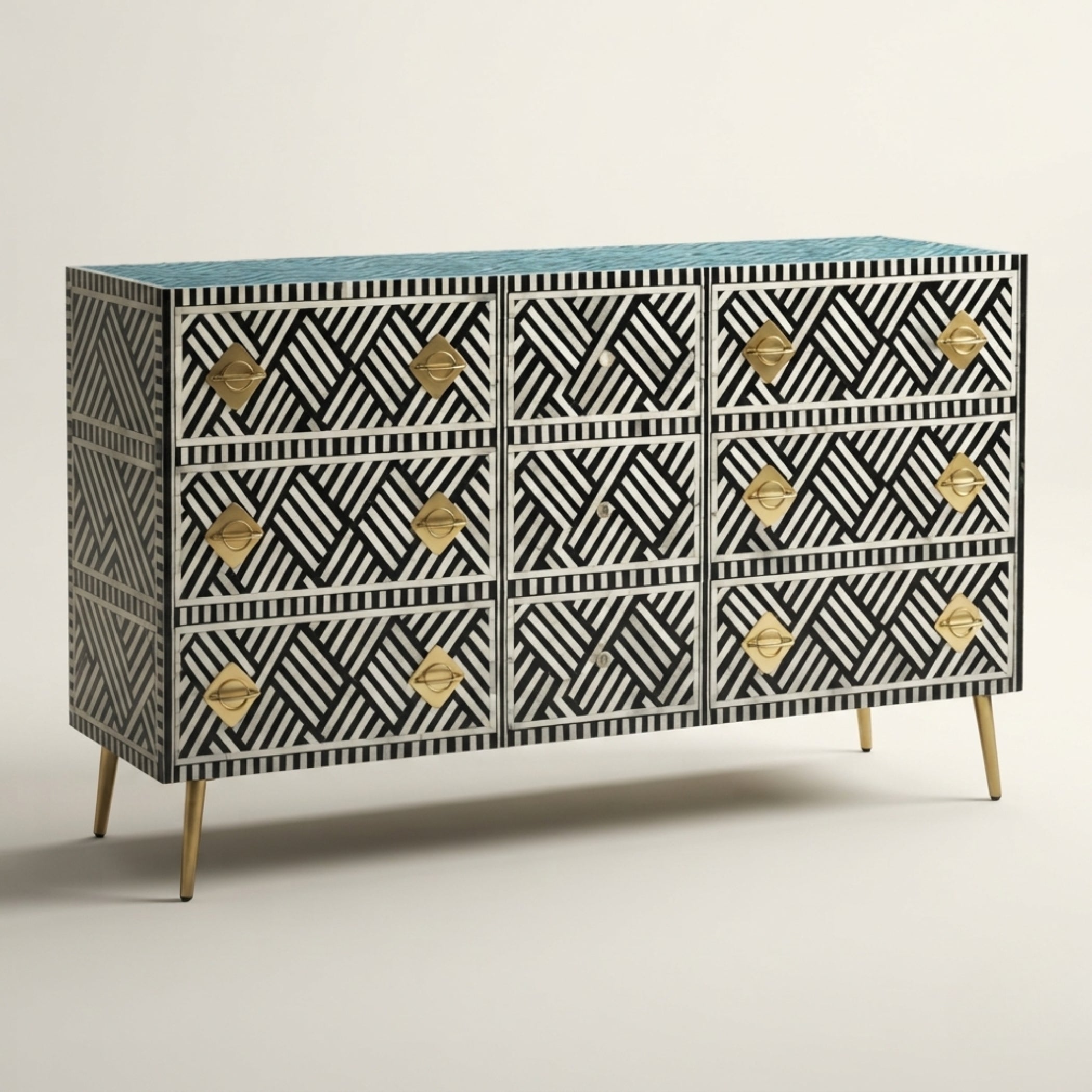 A mid-century modern sideboard with a black and white geometric bone-inlay pattern, gold-tone drawer pulls, and light wood legs, set against a neutral studio background.
