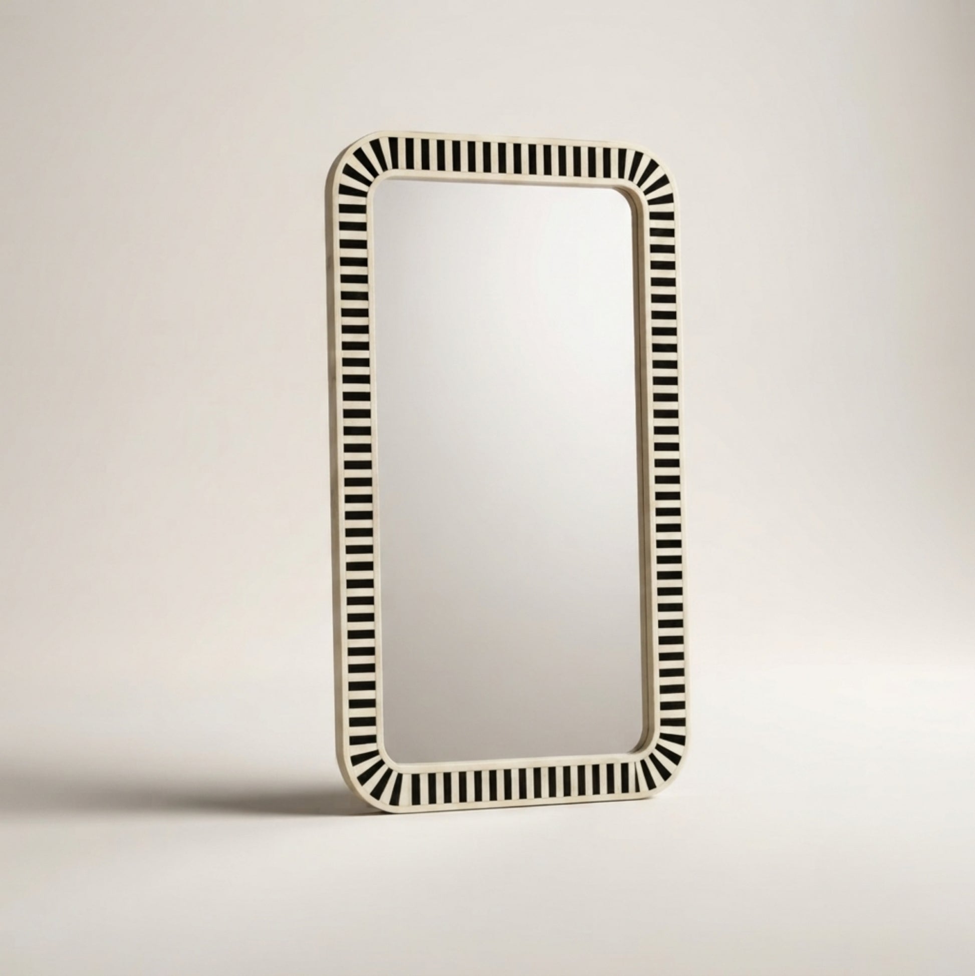 A rectangular wall mirror with a cream-colored frame featuring a repeating black and cream striped pattern around the border, shown against a neutral light gray background.