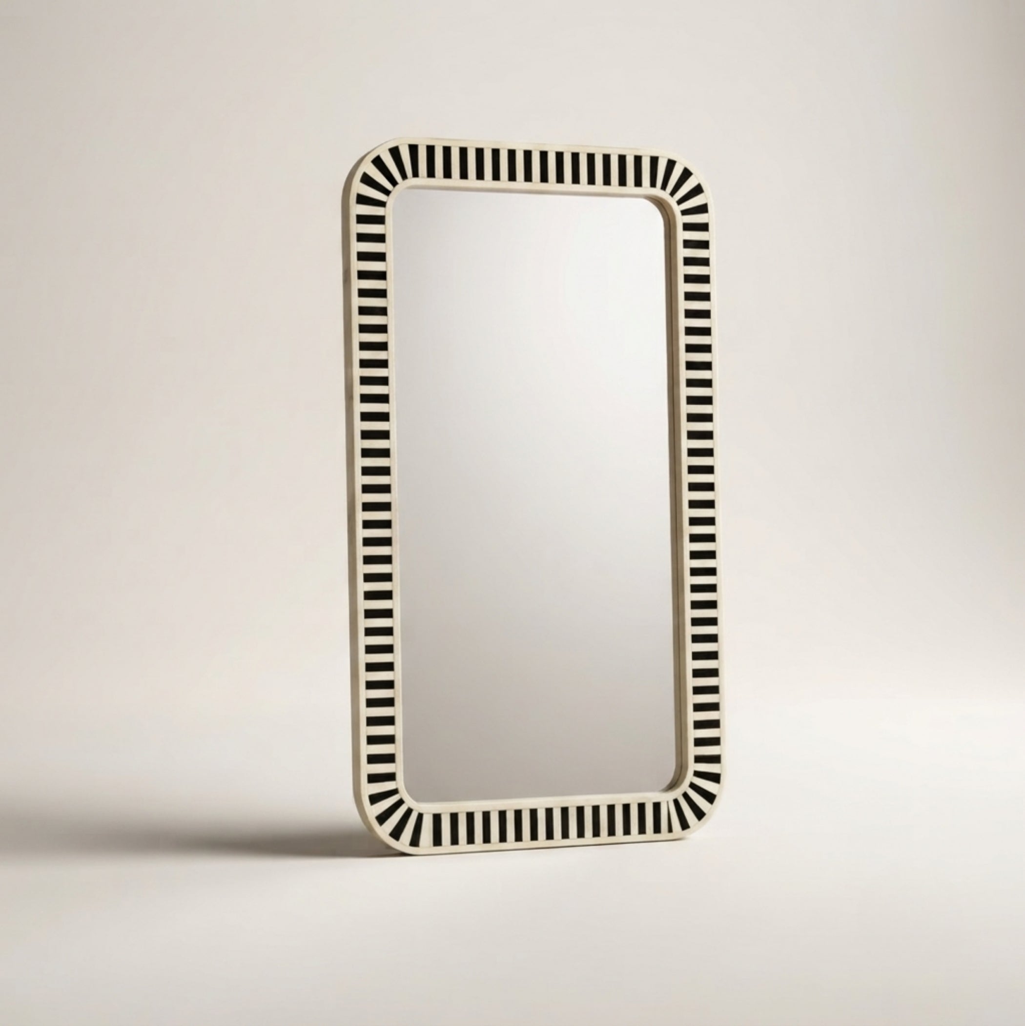 A rectangular wall mirror with a cream-colored frame featuring a repeating black and cream striped pattern around the border, shown against a neutral light gray background.