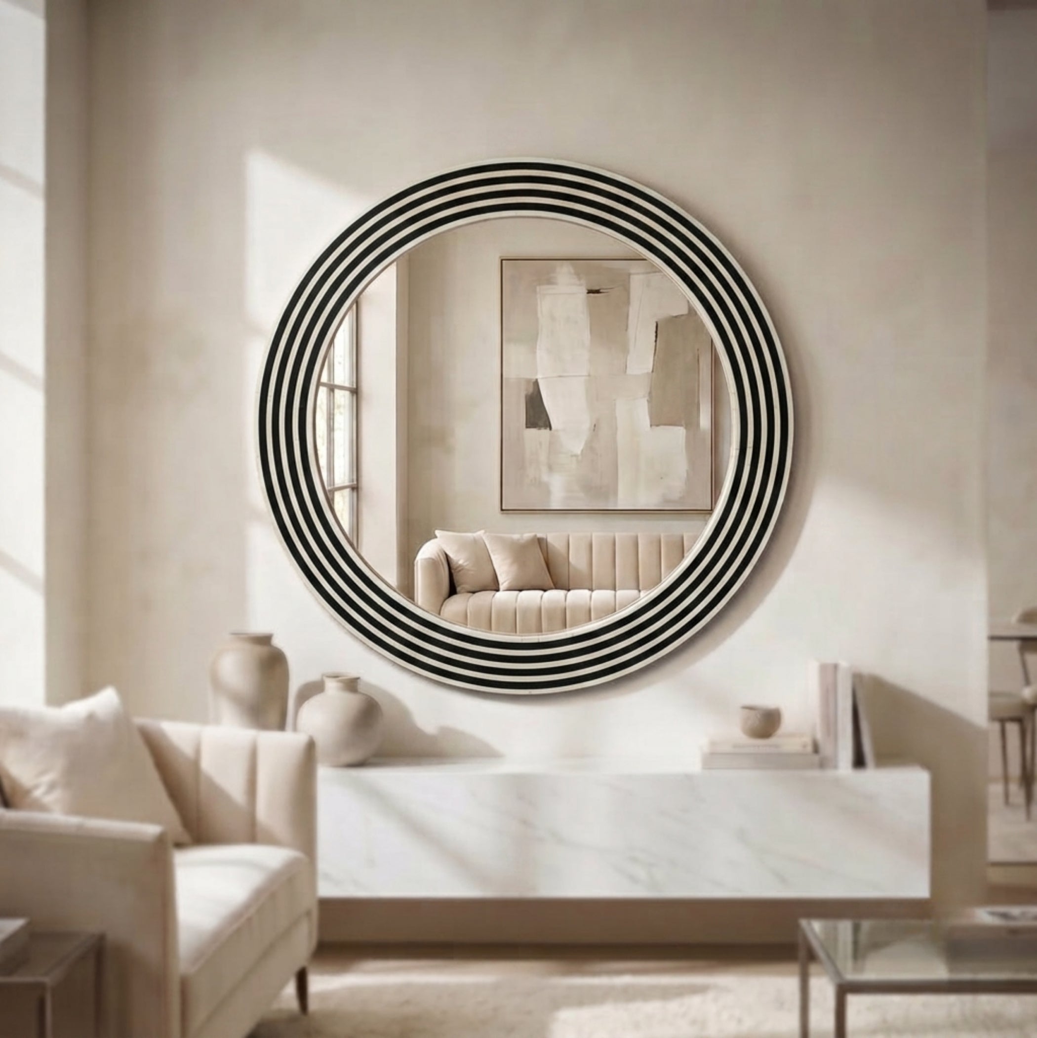 A round wall mirror with a bold black and white concentric stripe pattern, mounted on a beige wall in a modern, sunlit living room.