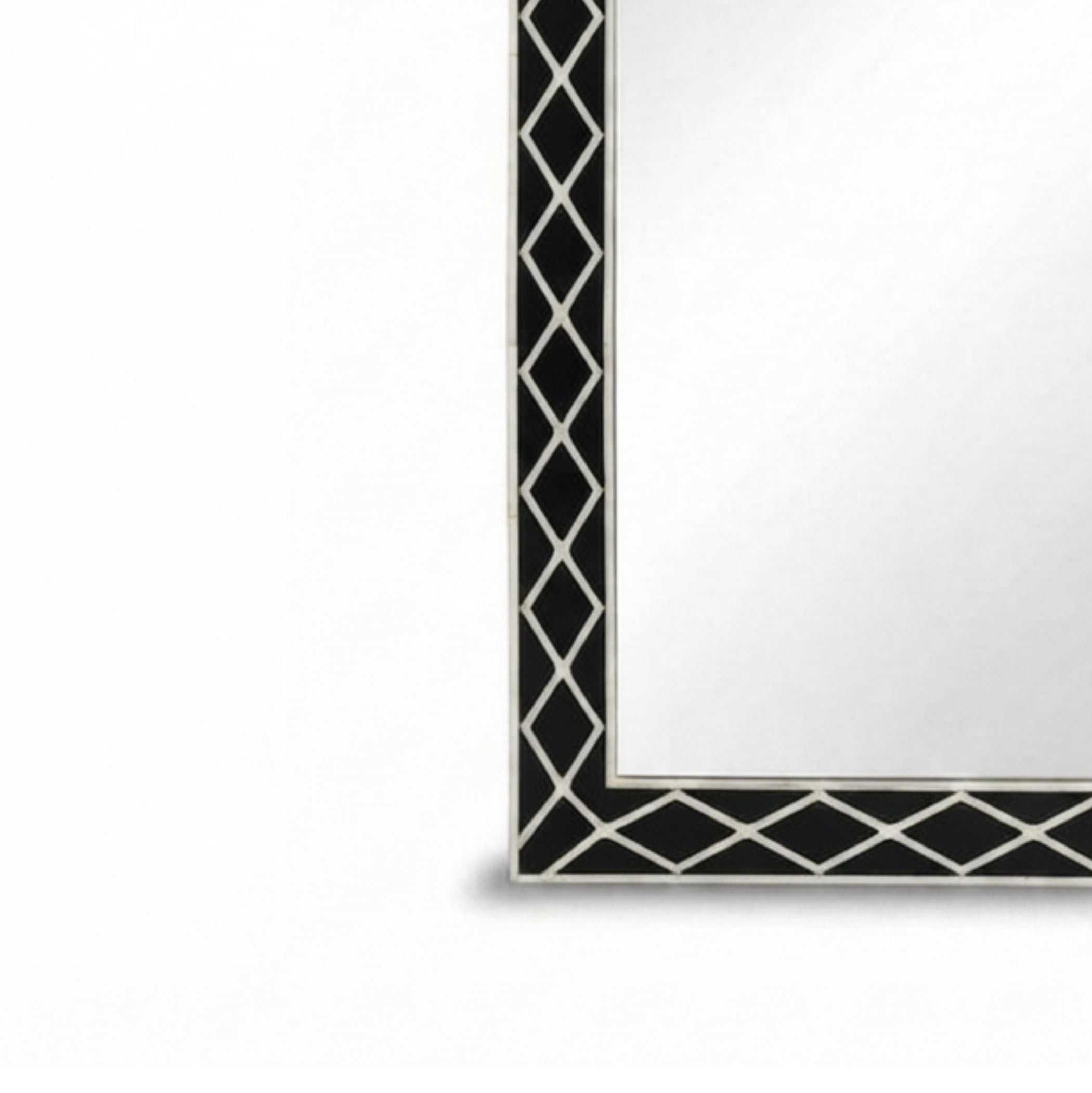 Close-up of a rectangular mirror showing part of its black and white geometric patterned frame on a white background.