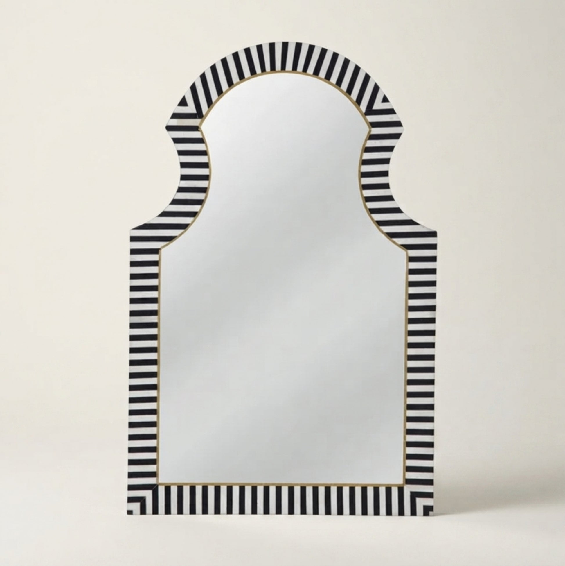 An arched wall mirror with a black and white striped frame and a thin gold inner border, shown against a plain light beige background.