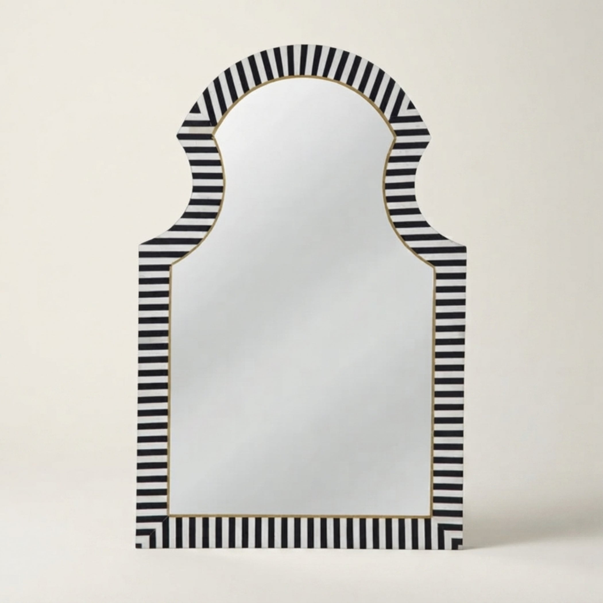 An arched wall mirror with a black and white striped frame and a thin gold inner border, shown against a plain light beige background.