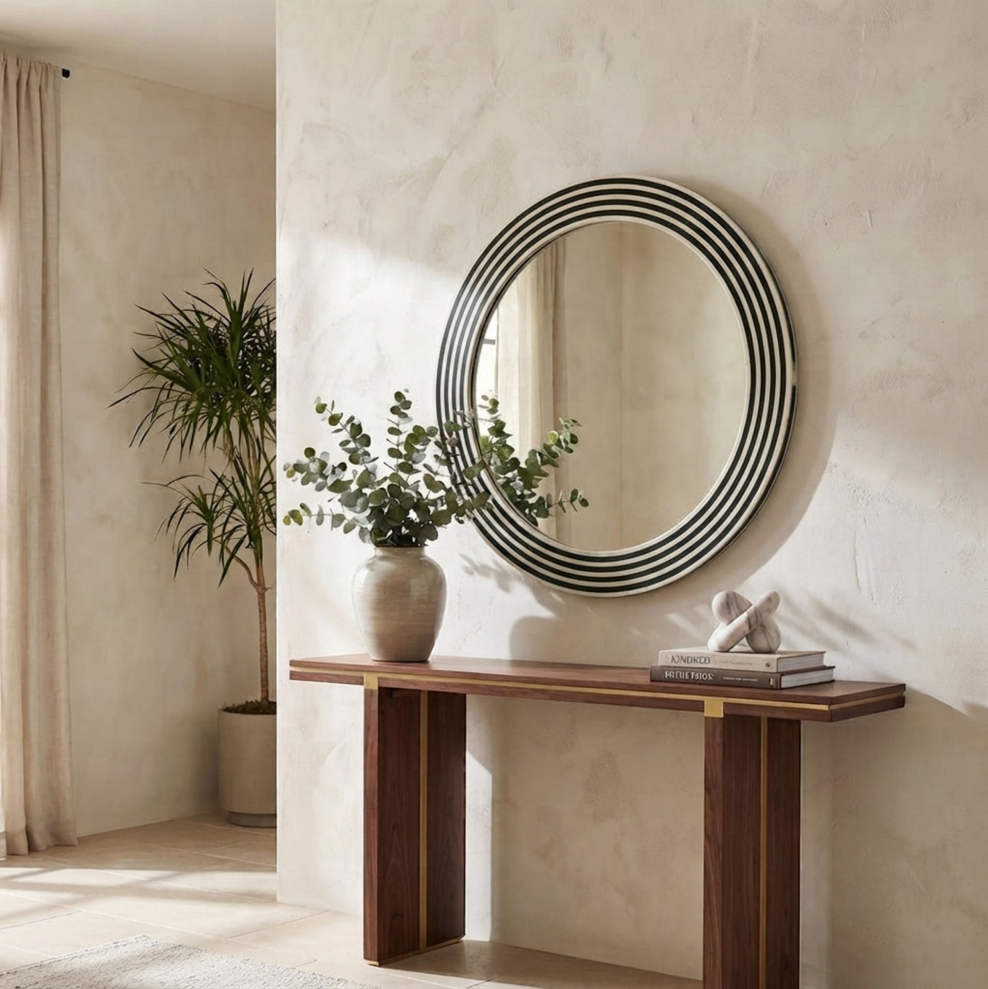Round wall mirror with concentric black and white stripes, mounted on a textured beige plaster wall above a wooden console table in a styled interior room.