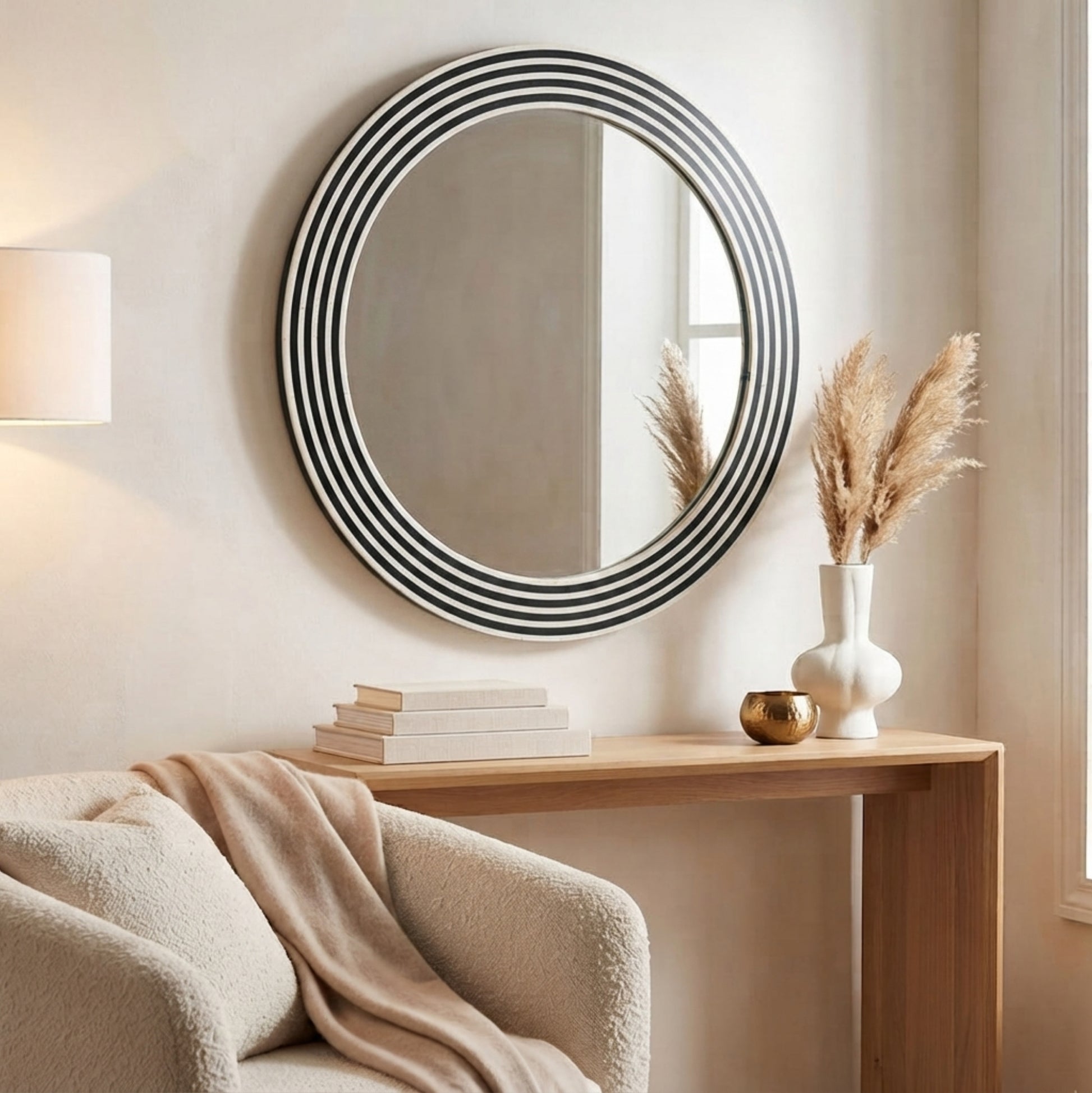 Round wall mirror with a black and white striped frame, styled in a warm, modern living room setting above a wooden console table.