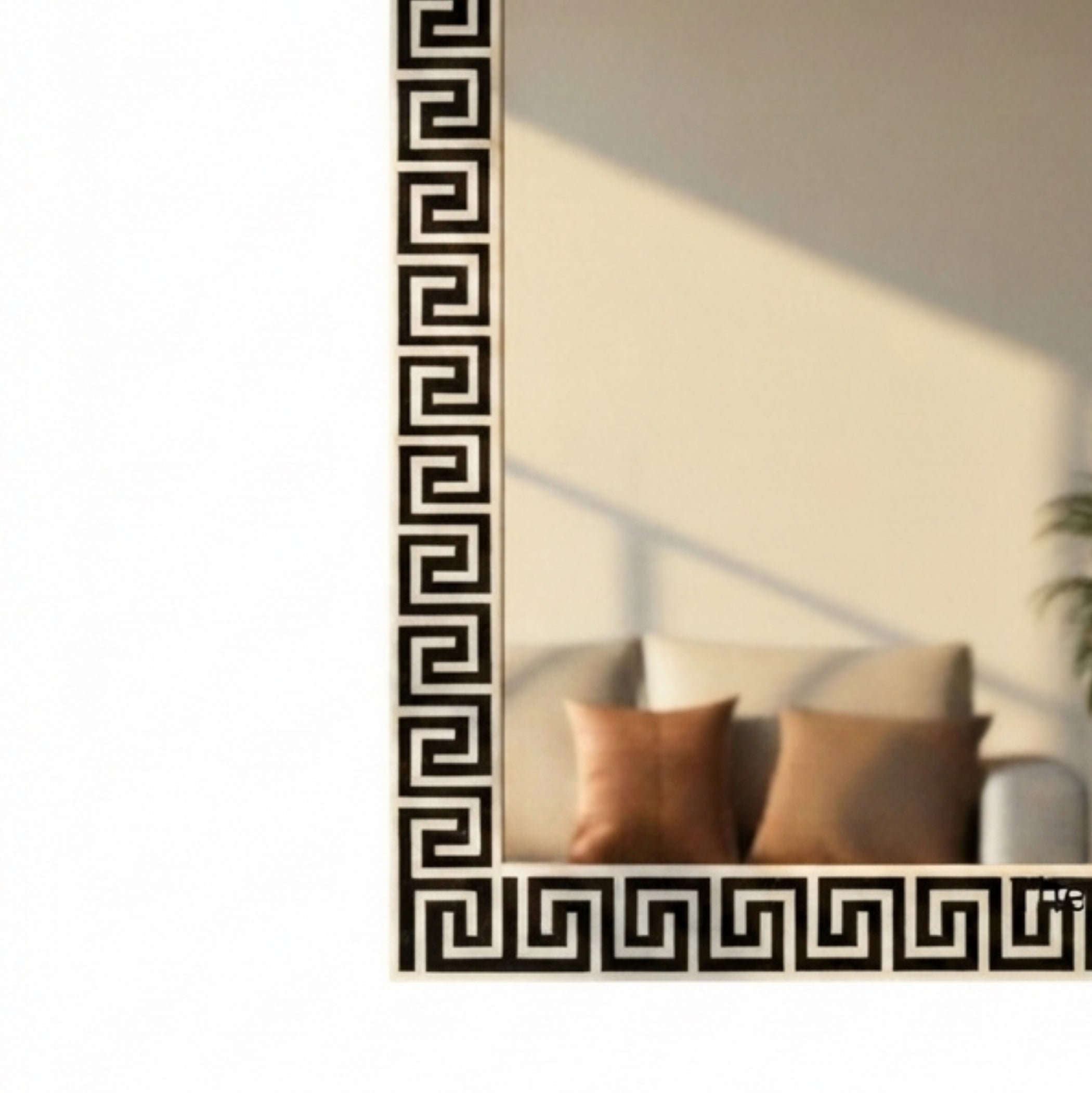 A rectangular mirror with a black and white Greek key geometric border, shown against a white background with its reflection displaying a beige sofa and brown pillows.