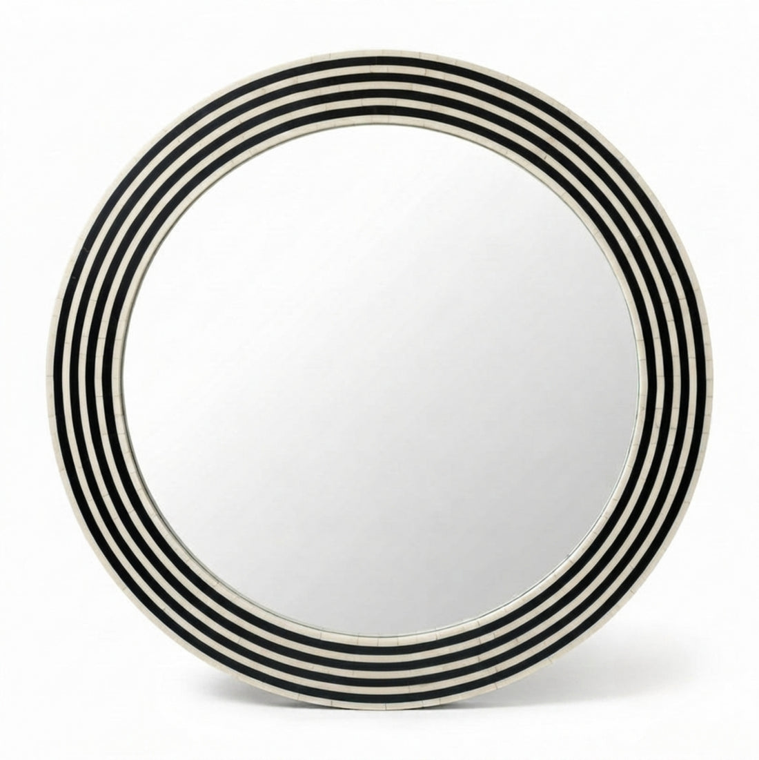 Round wall mirror with concentric black and white stripes, mounted on a textured beige plaster wall above a wooden console table in a styled interior room.