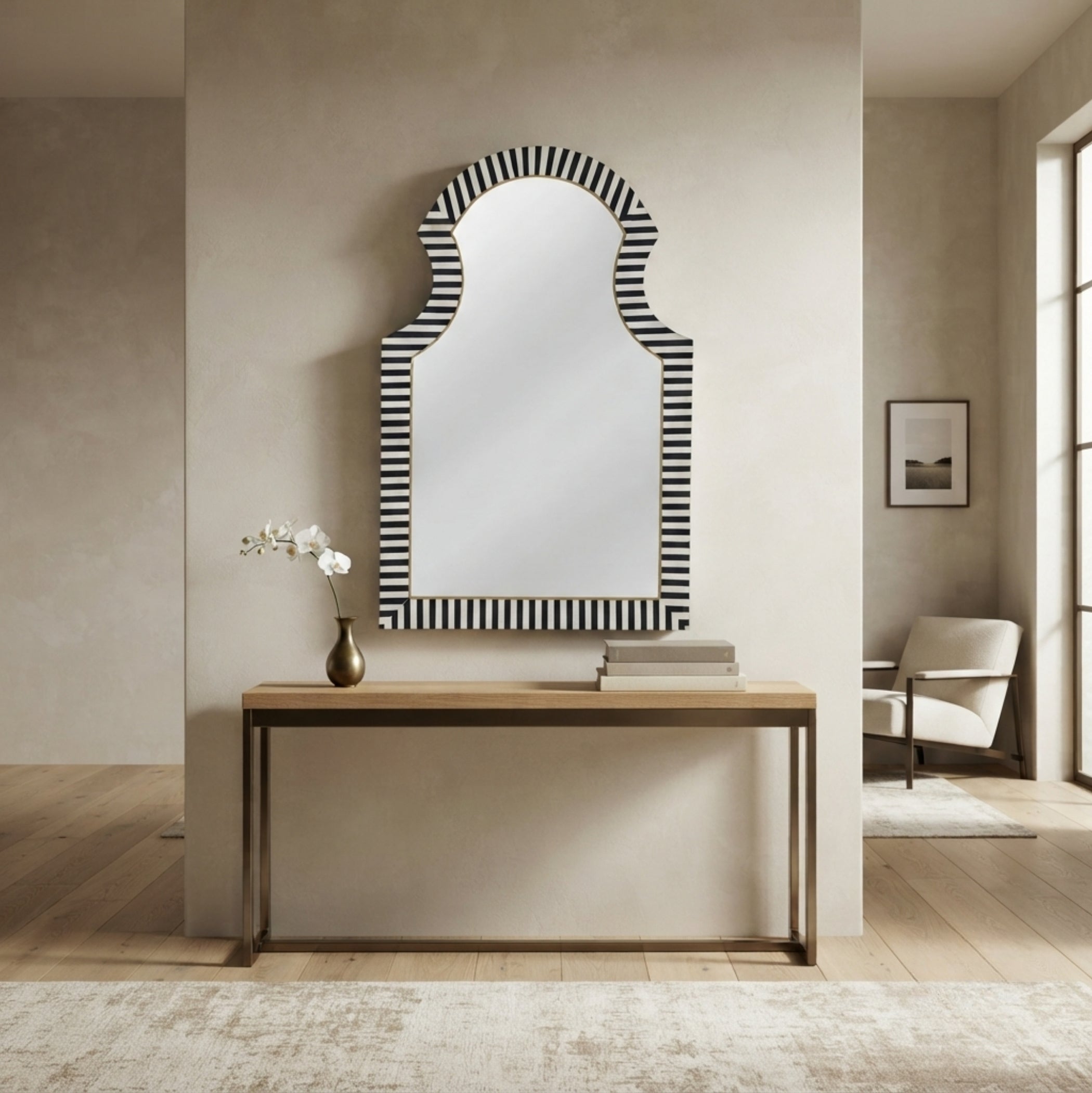 An arched wall mirror with a black and white striped border, styled on a light wood console table in a modern, neutral-toned living room.