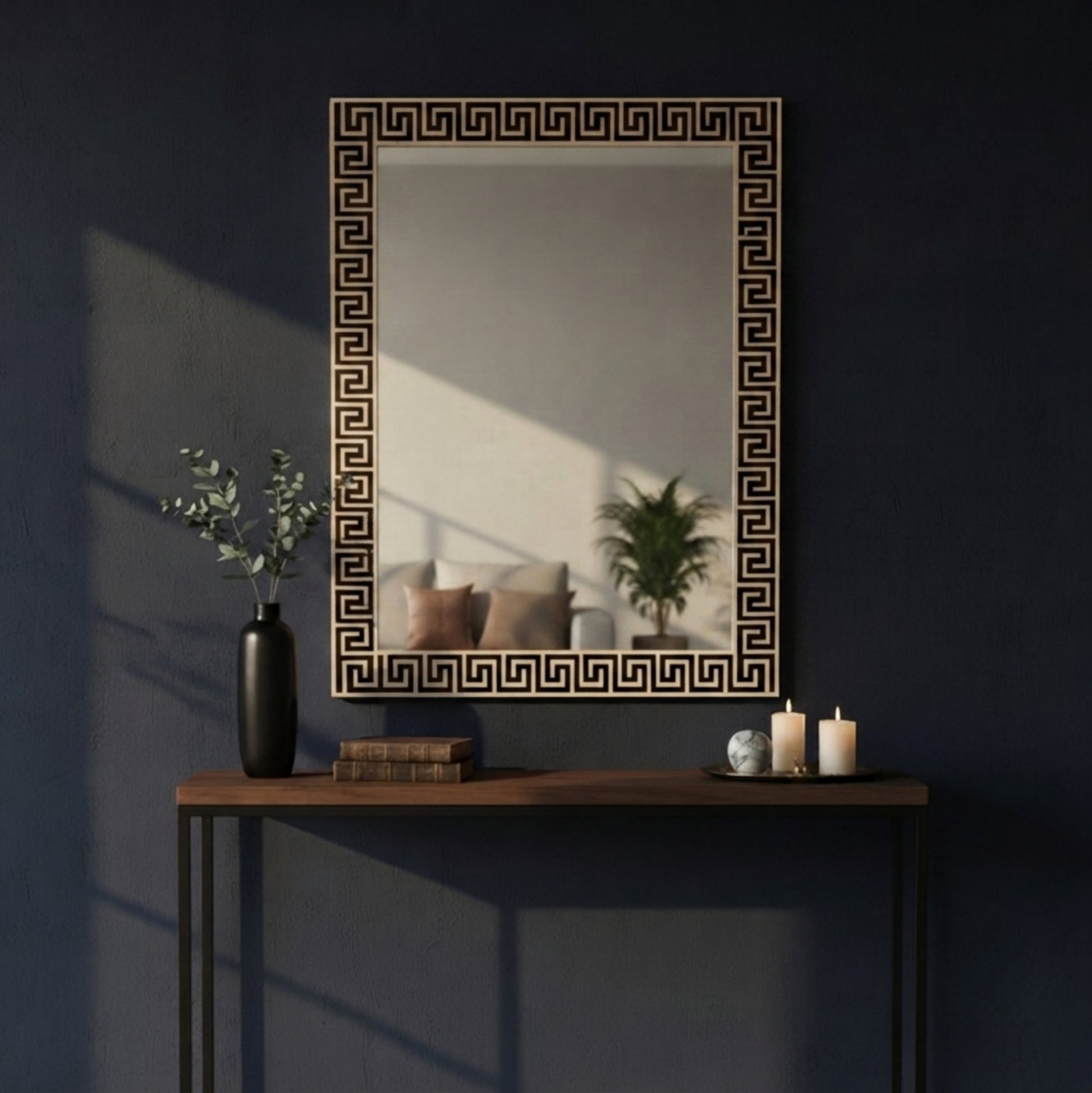 A rectangular wall mirror with a black Greek key pattern border, mounted on a dark navy blue wall above a wooden console table with decorative items.