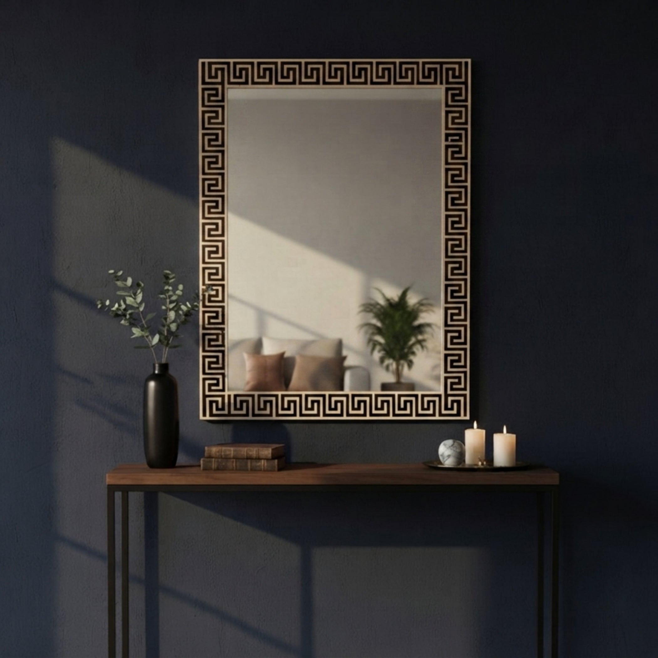 A rectangular wall mirror with a black Greek key pattern border, mounted on a dark navy blue wall above a wooden console table with decorative items.