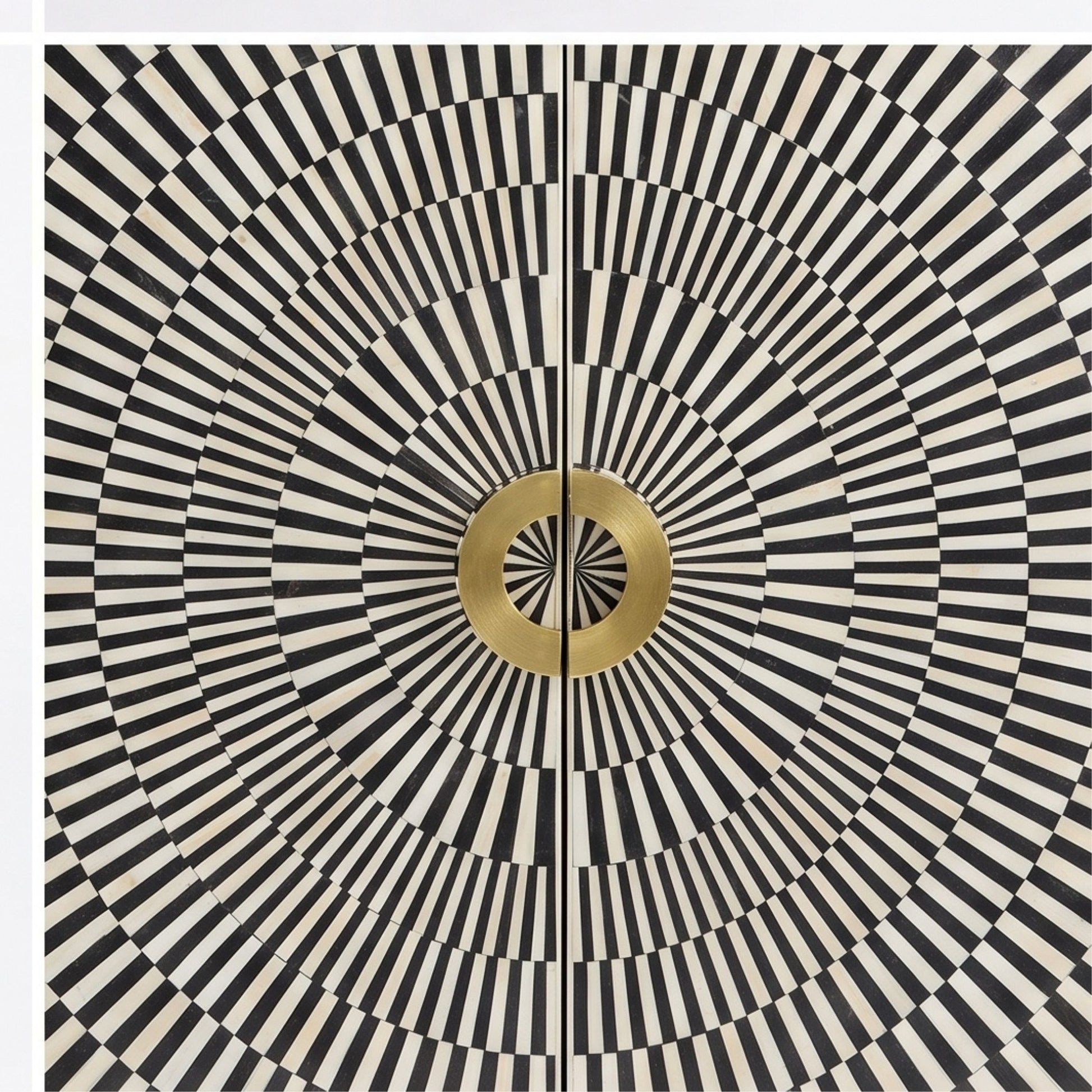 A square decorative panel or door featuring a bold black and off-white radial stripe pattern with concentric circles and a central metallic gold circular medallion.