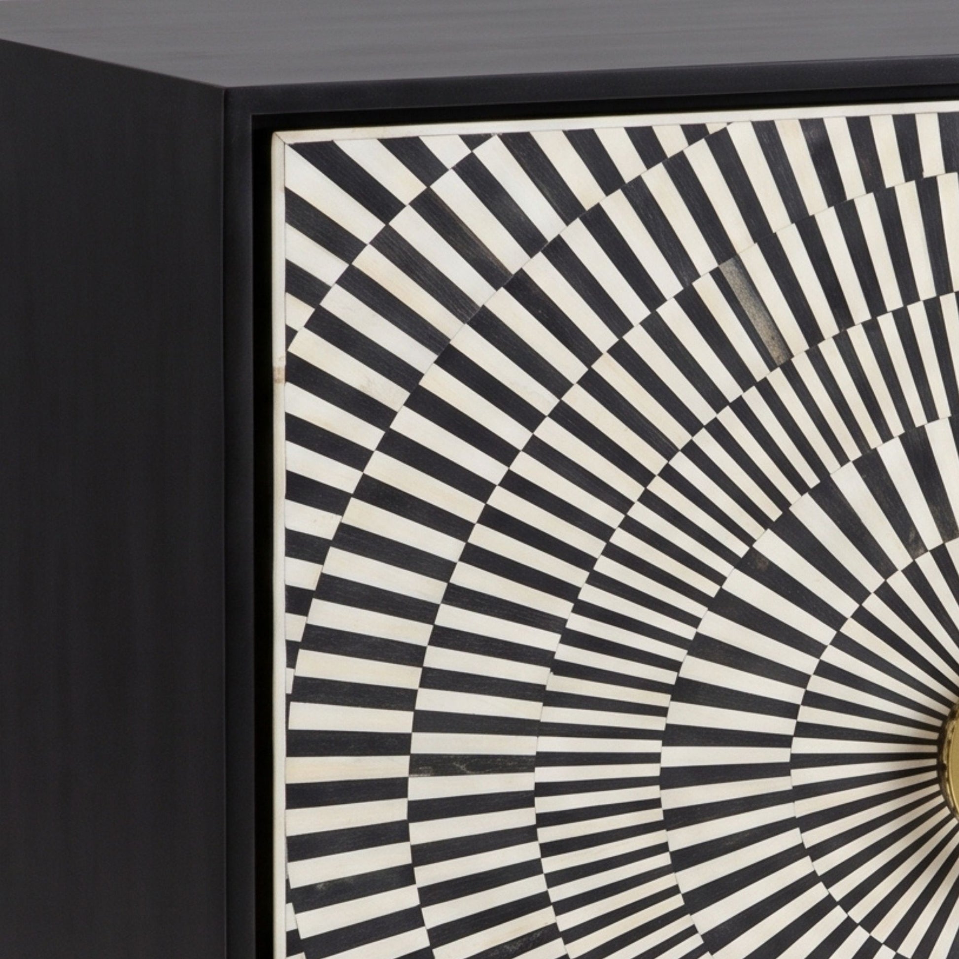 Close-up of a black cabinet or drawer front featuring a geometric black and off-white radial striped pattern on the door.