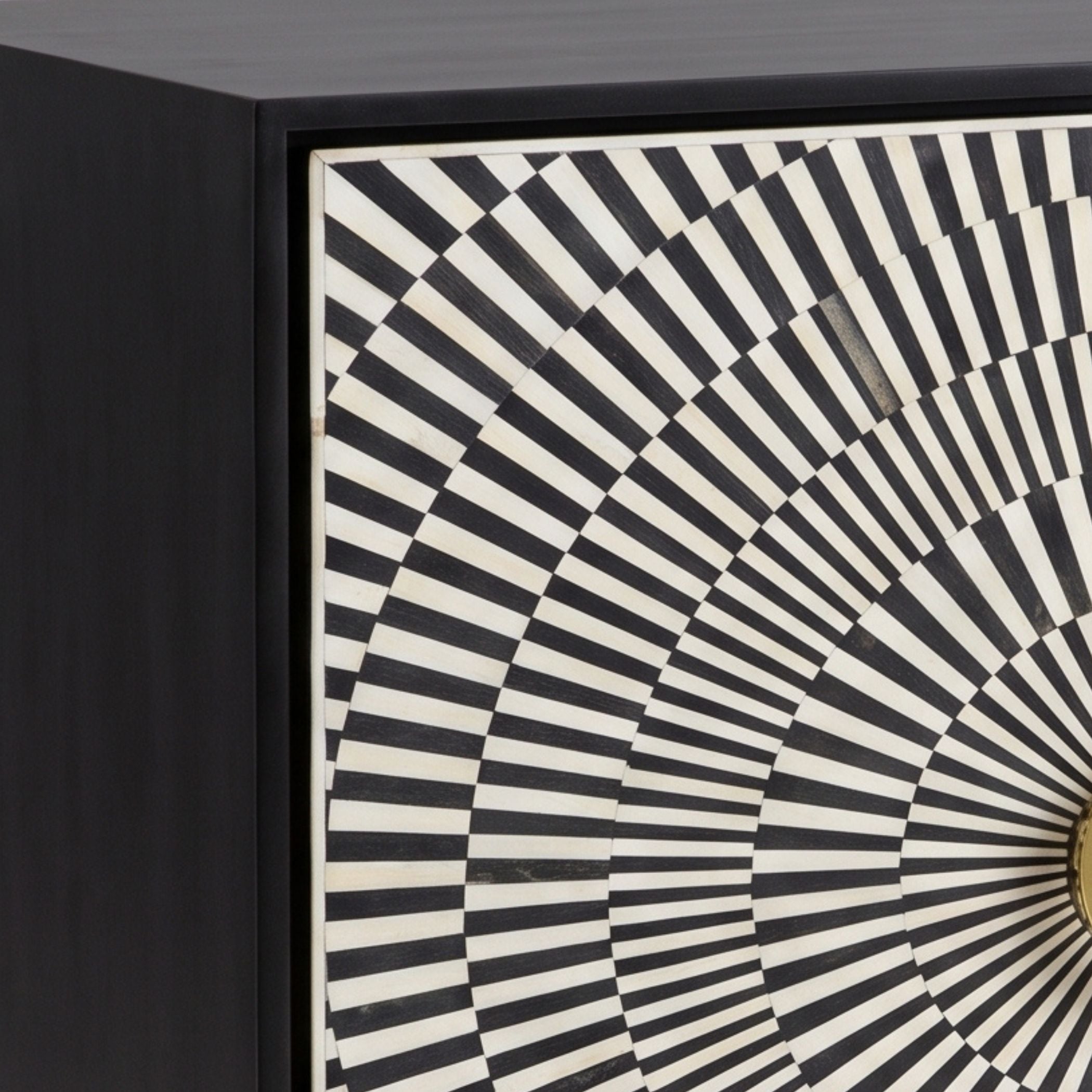 Close-up of a black cabinet or drawer front featuring a geometric black and off-white radial striped pattern on the door.