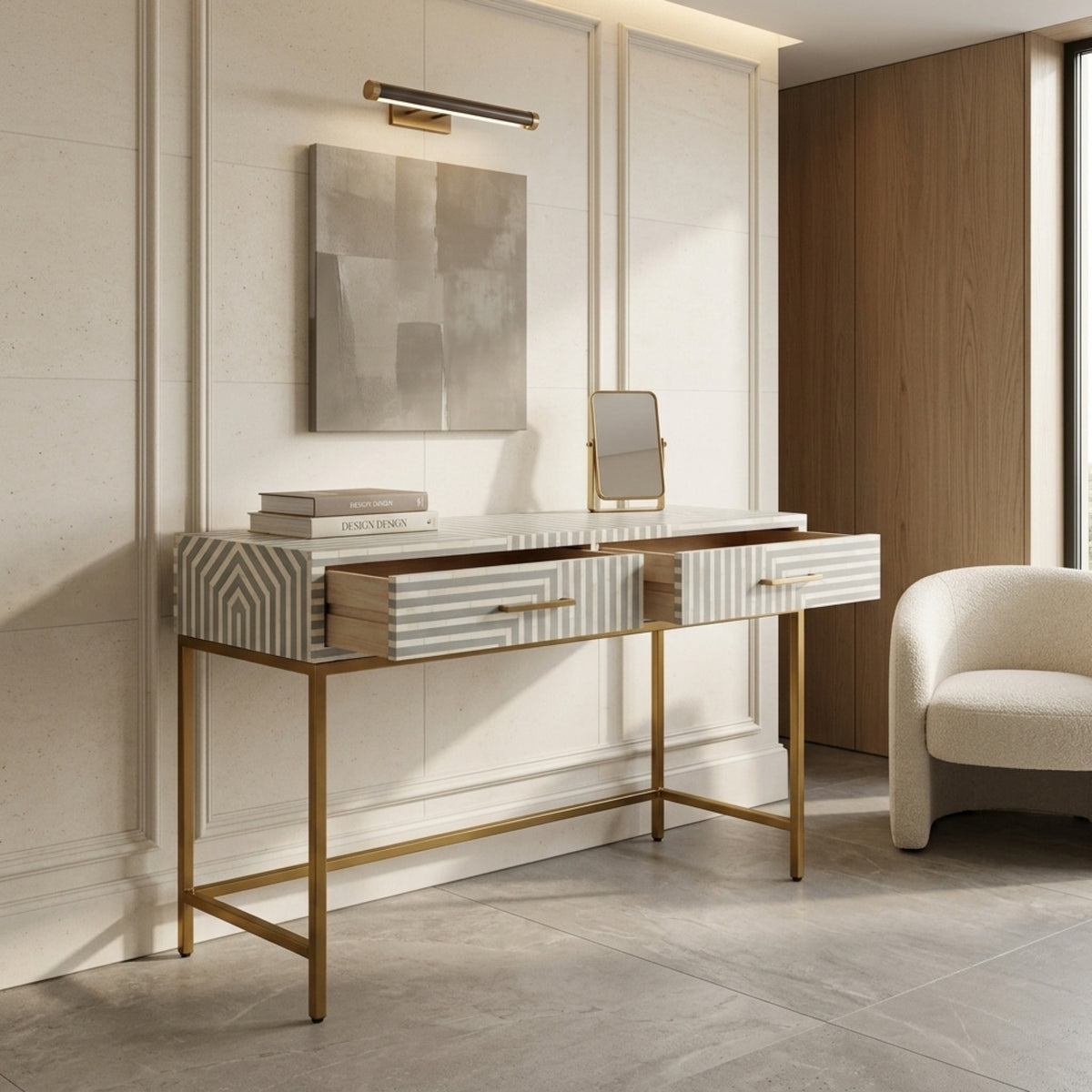 A modern console table with striped and geometric drawer fronts, a white marble top, and a gold metal frame, styled in a contemporary room next to a cream armchair.