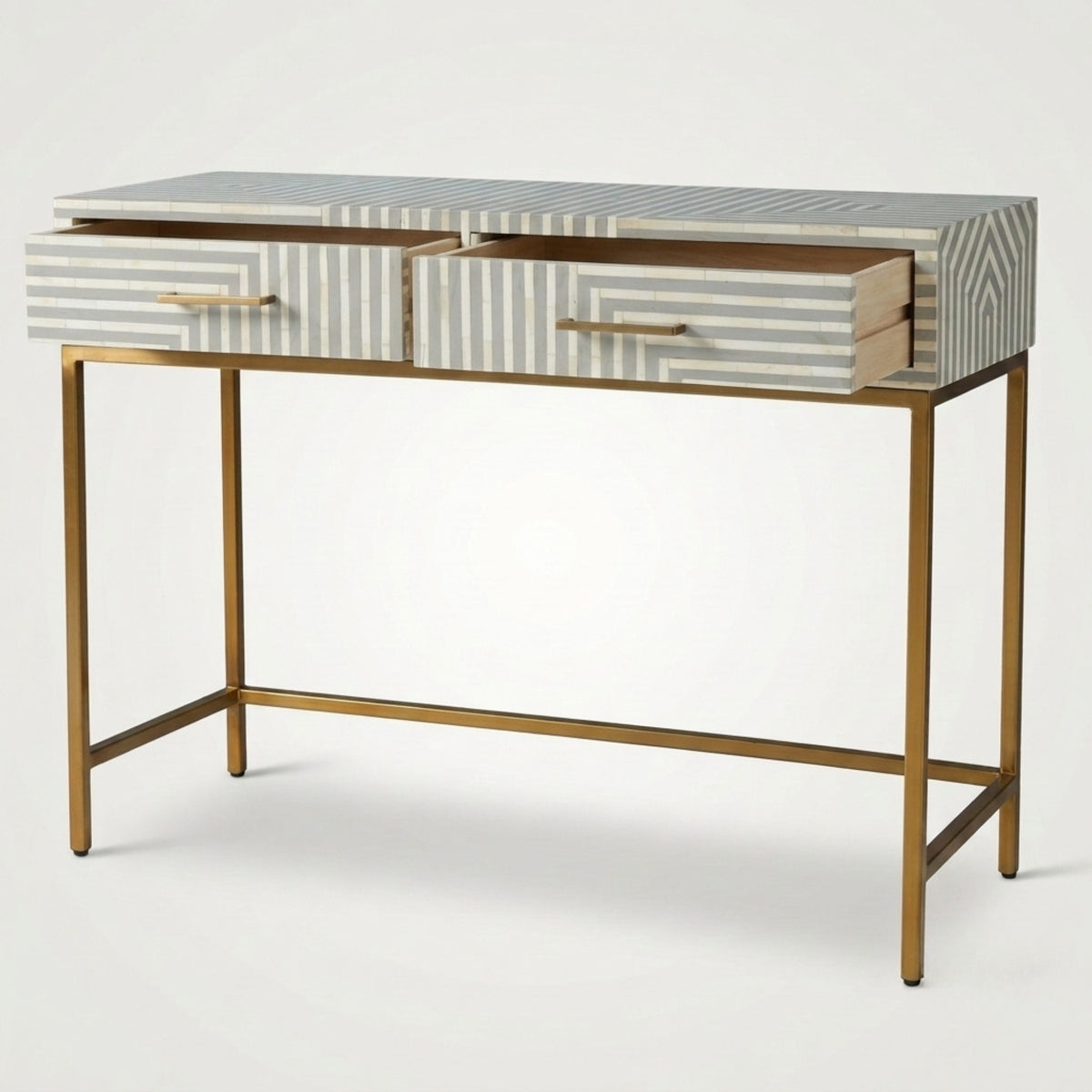 A modern writing desk with a gold metal frame, featuring two drawers with a beige and gray striped bone-inlay finish and slim gold handles, set against a plain light gray background.
