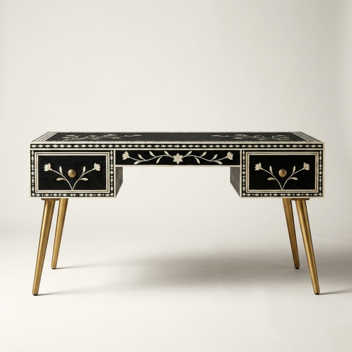 A black console table with two drawers, decorated with white mother-of-pearl floral inlays and featuring tapered gold-tone legs, shown against a neutral light gray background.