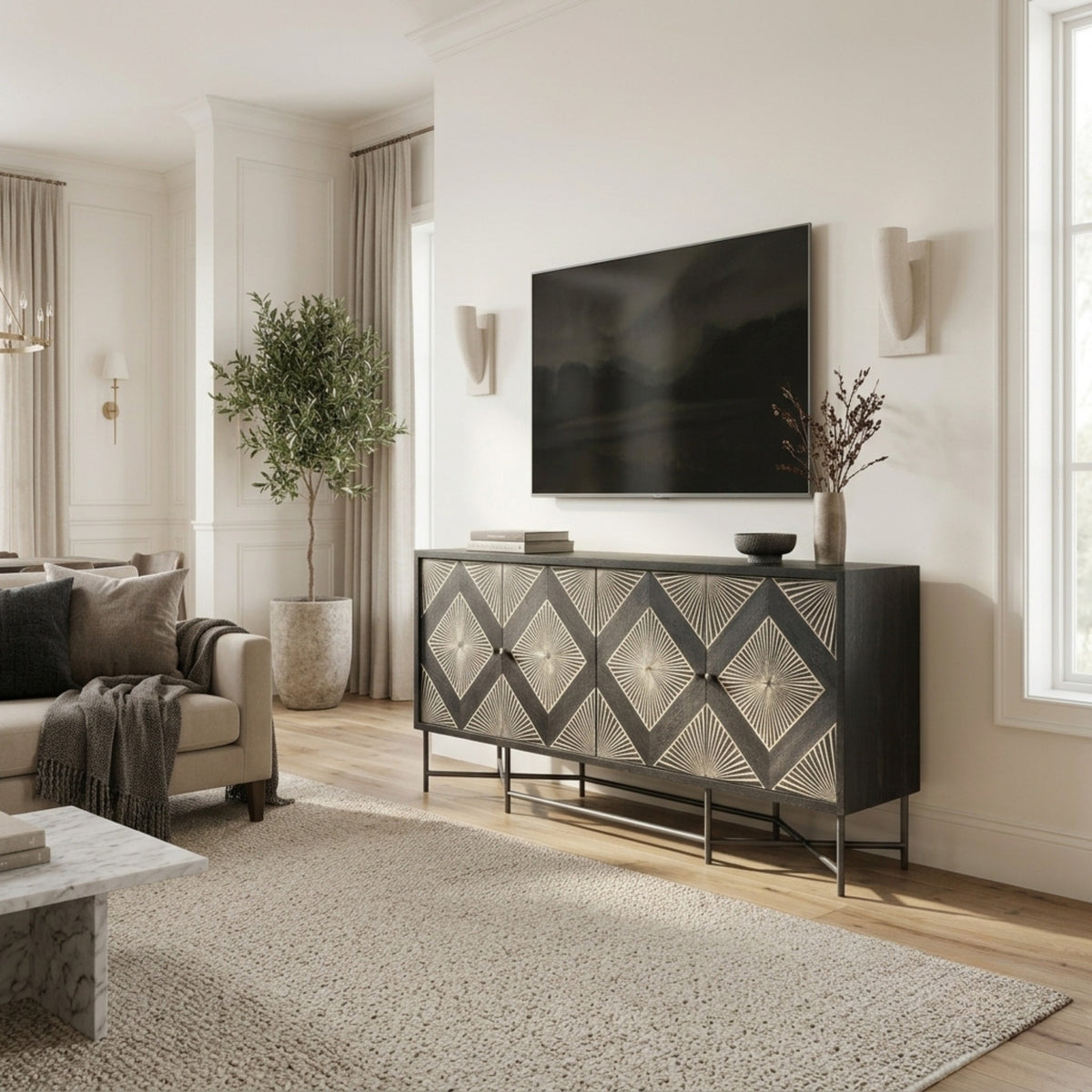 A modern black sideboard with a silver geometric diamond pattern on the doors, styled in a bright, contemporary living room next to a beige sofa and under a wall-mounted flat-screen TV.