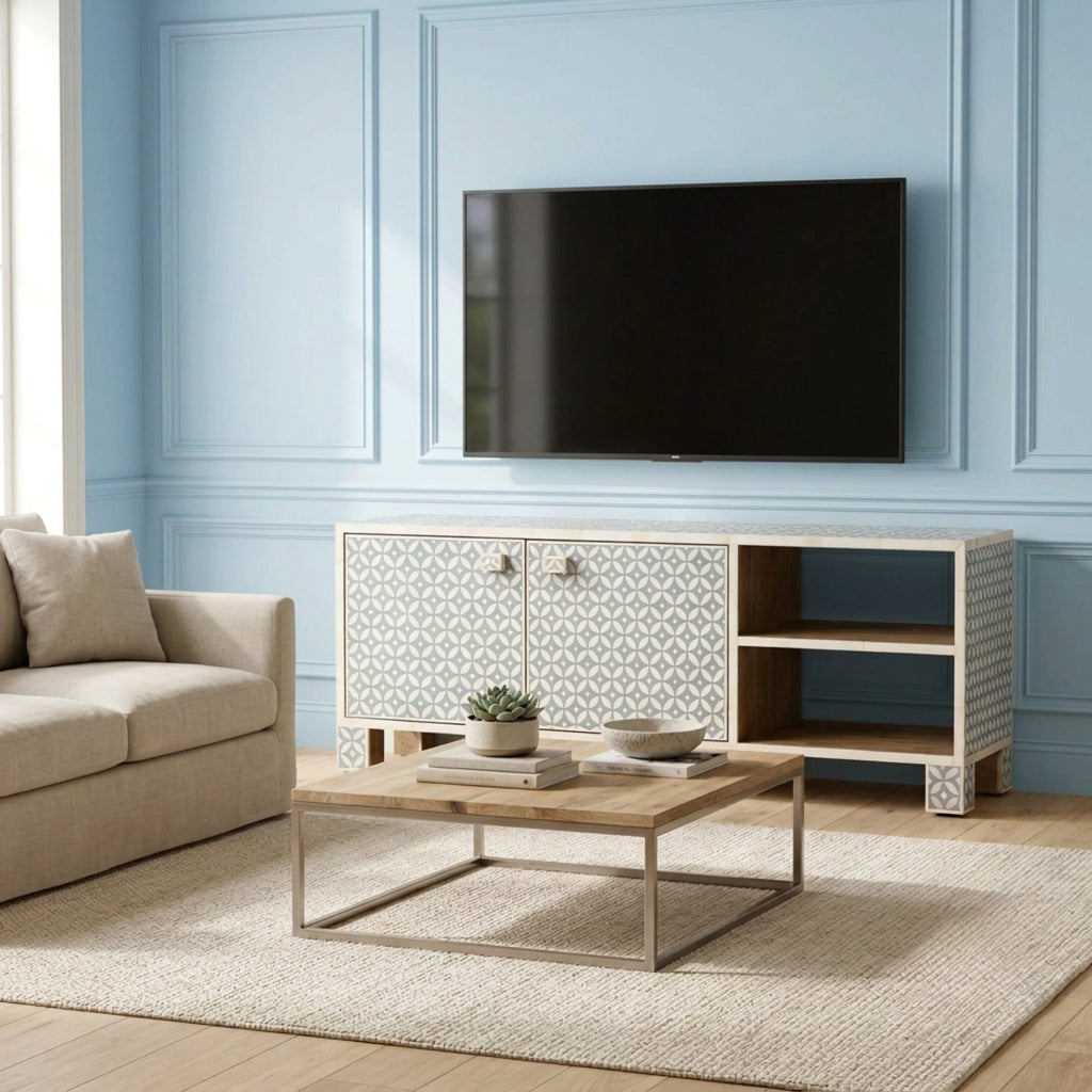 A modern light wood and patterned media console in a styled living room setting with a blue paneled wall, beige sofa, and wooden coffee table.