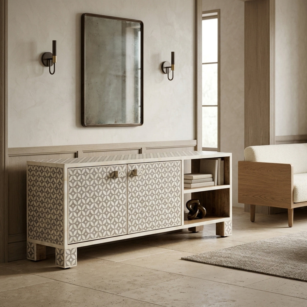 A modern sideboard cabinet with geometric patterned bone inlay doors, open shelving, and carved legs, styled in a minimalist, warm-toned entryway or living space next to a sofa and mirror.