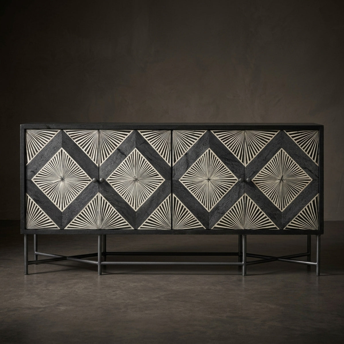 A modern sideboard or credenza with four doors, featuring a black and white geometric bone-inlay pattern with radiating starburst designs. The cabinet has a black metal frame and legs, set against a dark, minimalist studio background.