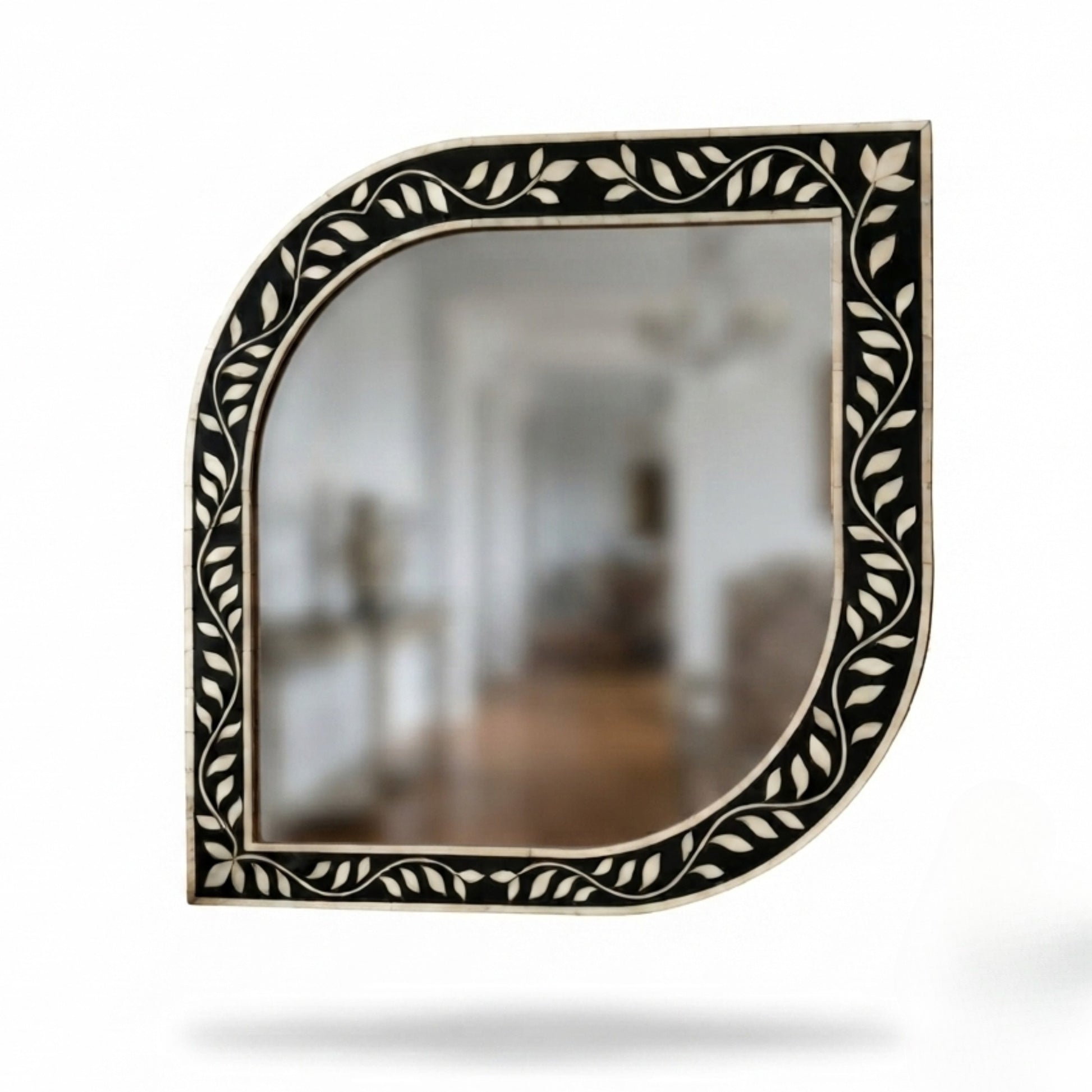 Decorative wall mirror with a curved, shield-like silhouette and an ornate black and beige leaf-patterned frame, shown against a plain white background.