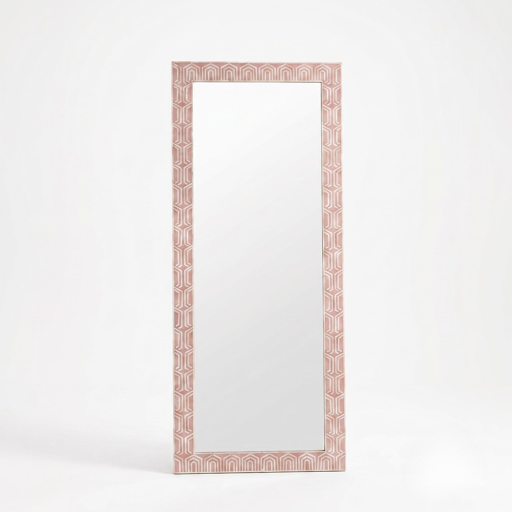 A tall rectangular floor mirror with a decorative geometric border in a dusty pink and white pattern, set against a clean white background.