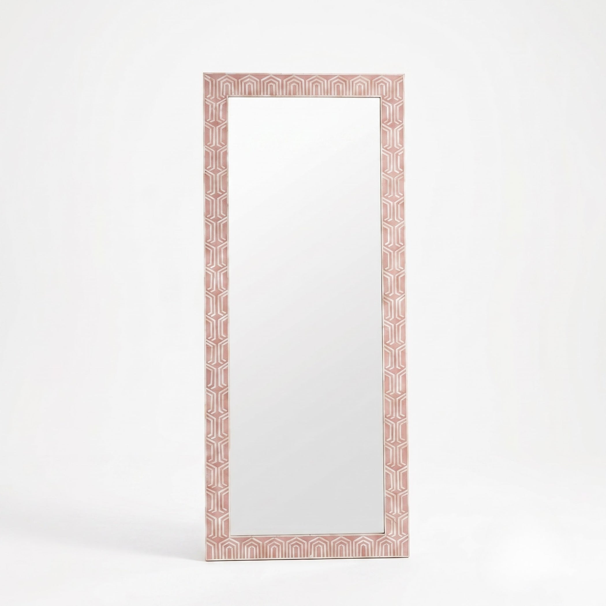 A tall rectangular floor mirror with a decorative geometric border in a dusty pink and white pattern, set against a clean white background.