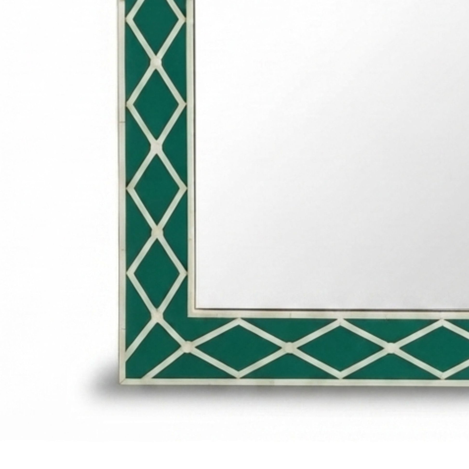 Close-up of a decorative mirror corner with a green and white geometric trellis border on a white background.