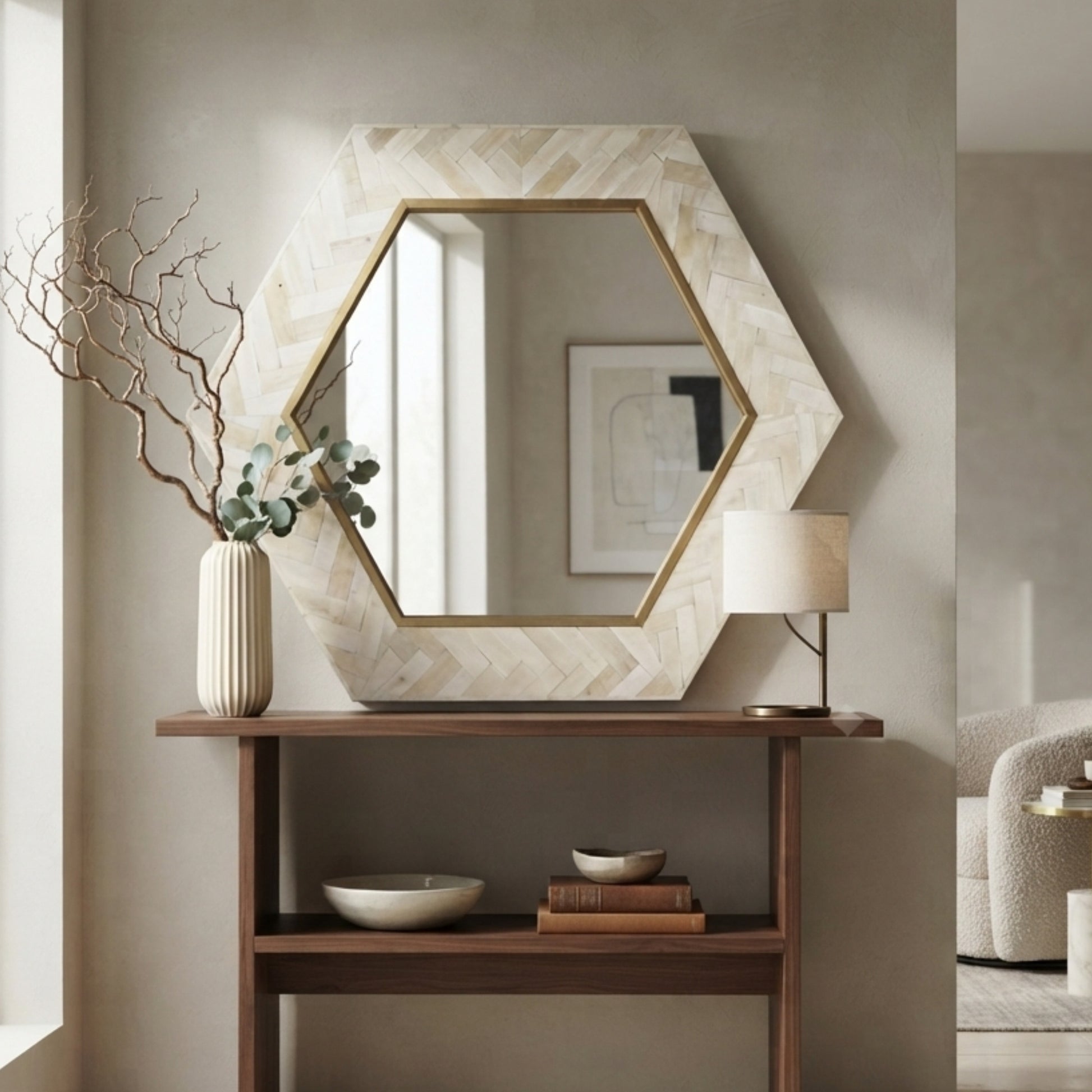 Hexagonal wall mirror with a light beige herringbone-patterned frame and a gold inner border, displayed above a wooden console table in a styled interior setting.