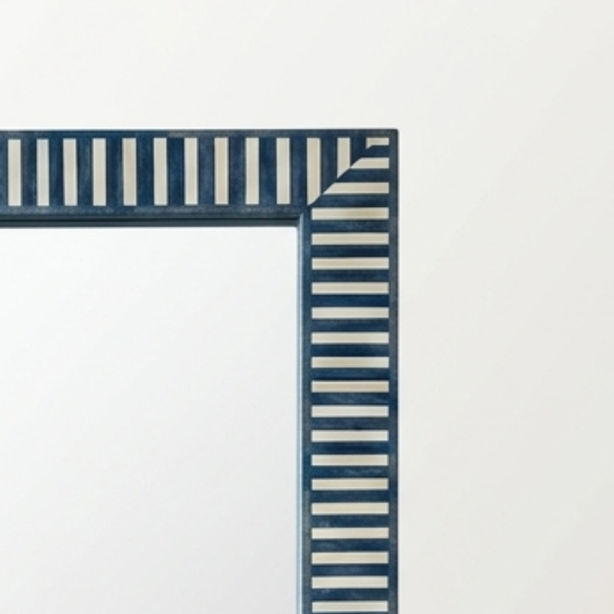 Close-up of a decorative rectangular frame corner with alternating vertical navy and white stripes, shown against a plain light background.