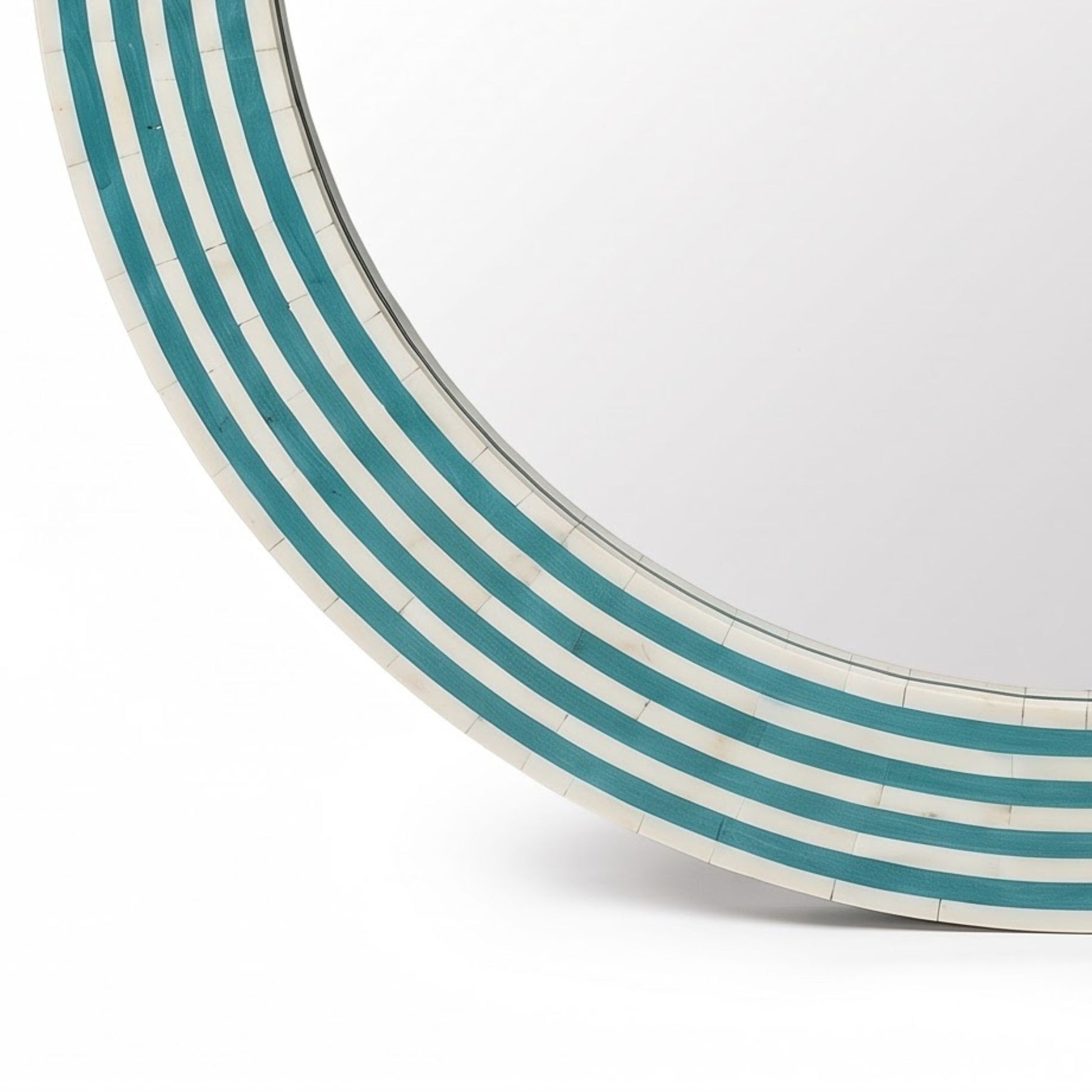 A close-up of a round wall mirror with a curved frame made of alternating white and teal inlay segments, shown against a plain white background.