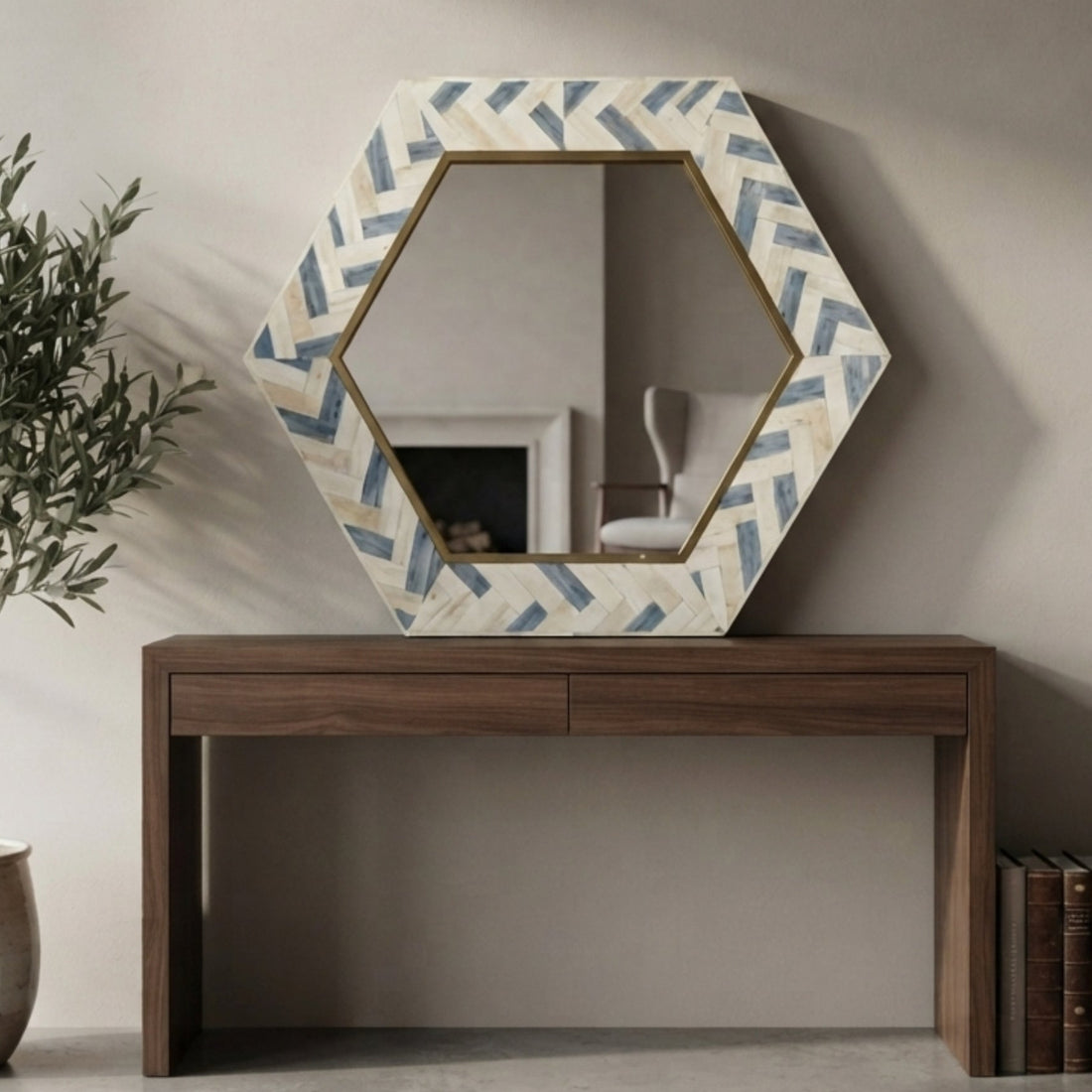 Hexagonal wall mirror with a cream and blue chevron patterned frame, styled on a dark wood console table against a beige wall.