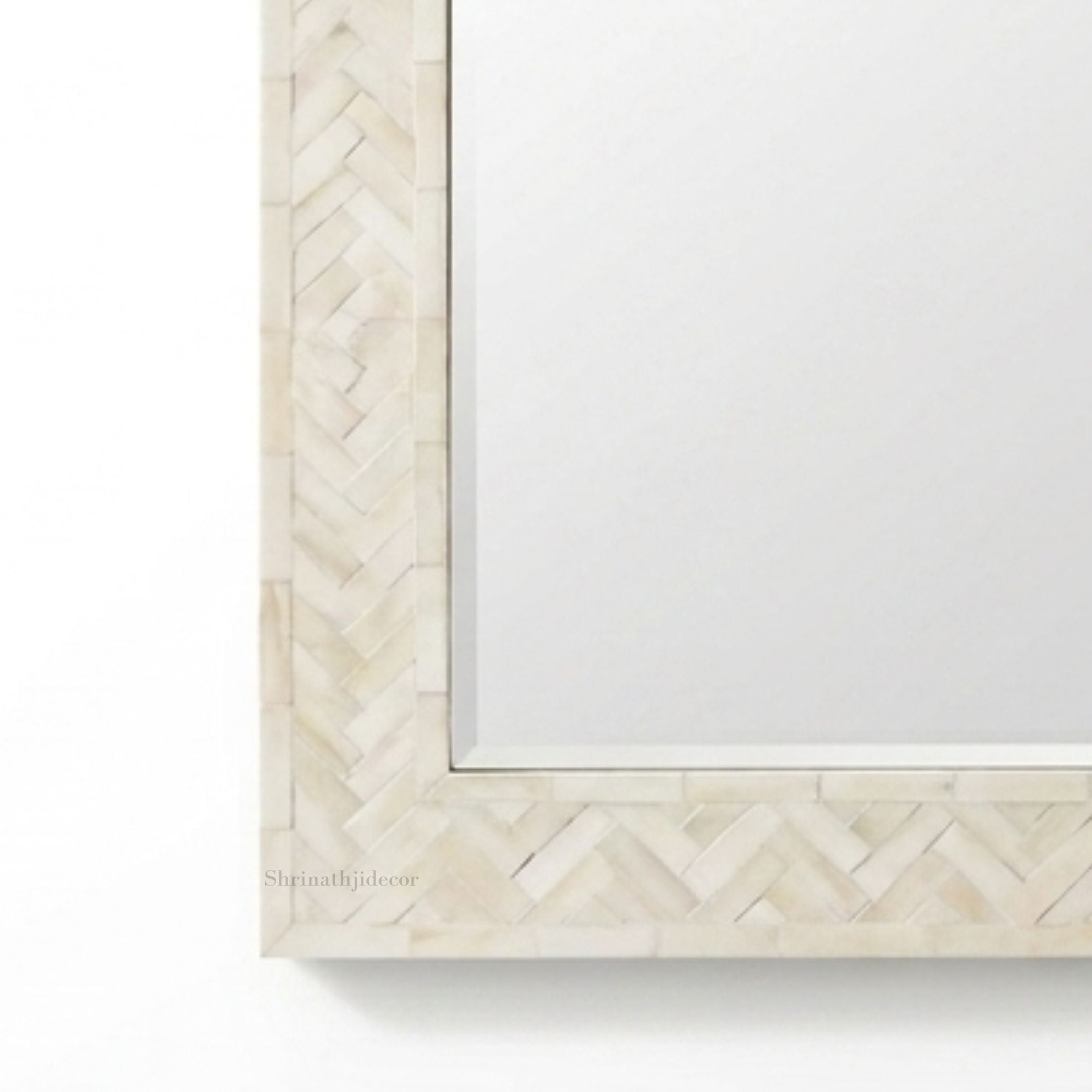 Close-up of a decorative rectangular mirror frame with a light beige herringbone inlay border on a white background.