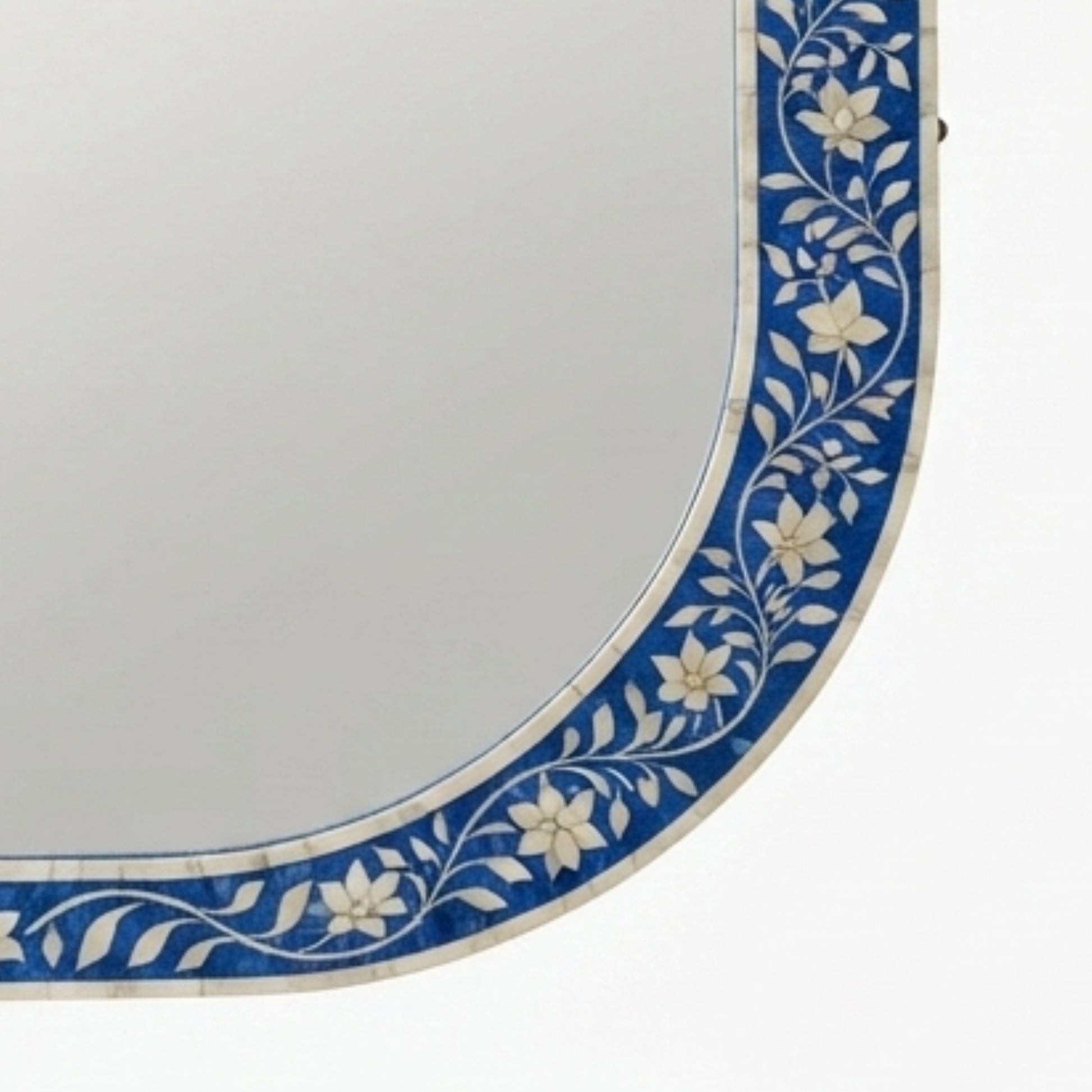 Close-up of a decorative wall mirror corner showing a blue and white floral mosaic border.