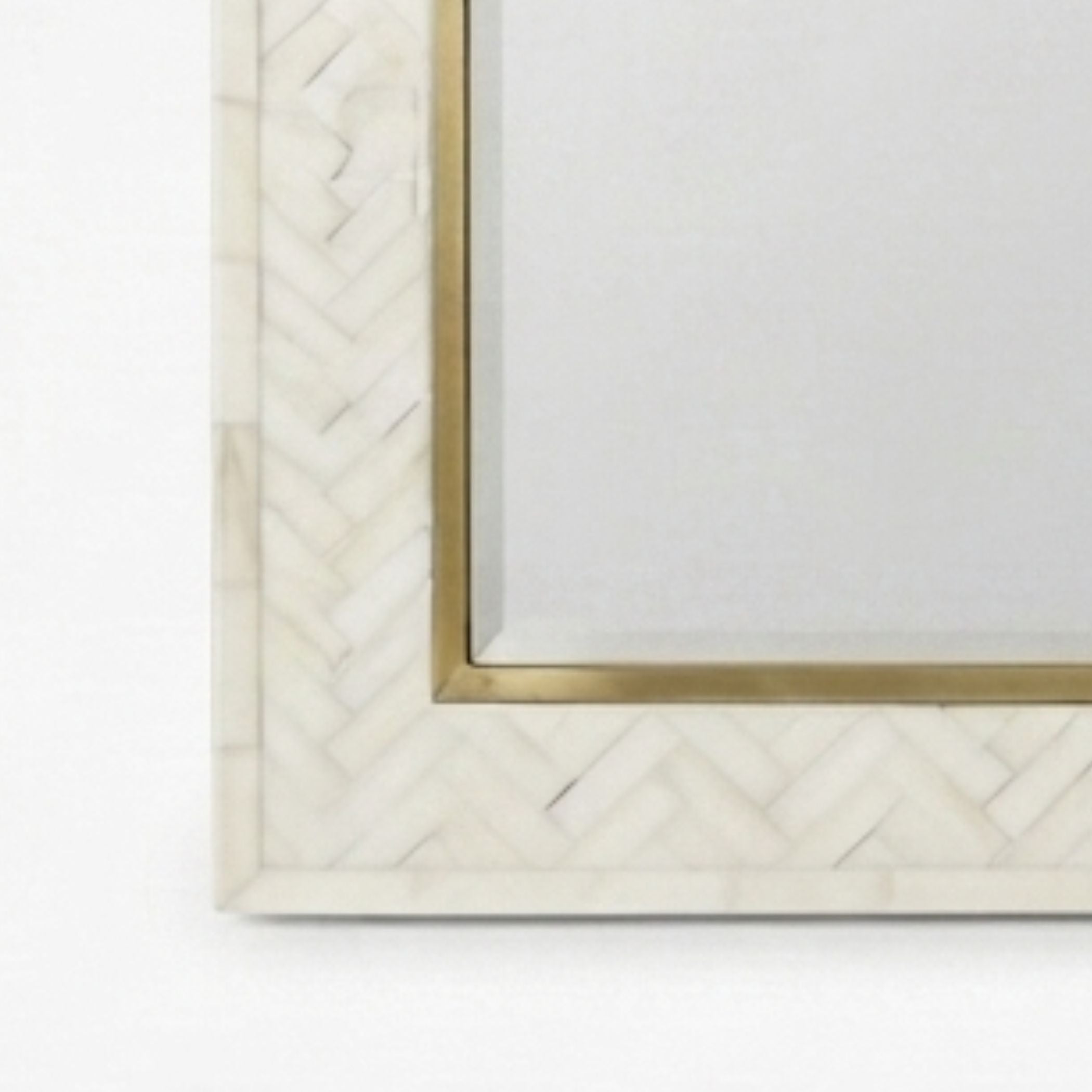 Close-up of a rectangular mirror with a white herringbone-patterned frame and a gold inner border, shown against a white background.