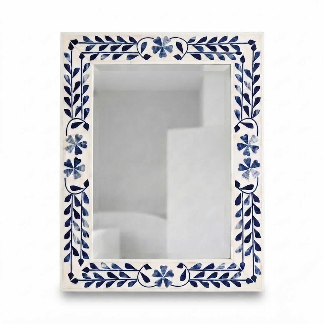 A rectangular wall mirror with a white frame decorated with blue floral and leaf motifs, hanging on a textured gray wall above a light wood console table with decorative items.