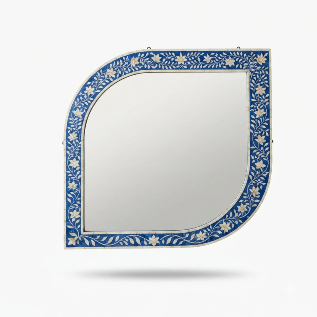 An arched wall mirror with a blue and white floral inlay frame, mounted on a beige wall above a wooden console table in a styled interior setting.