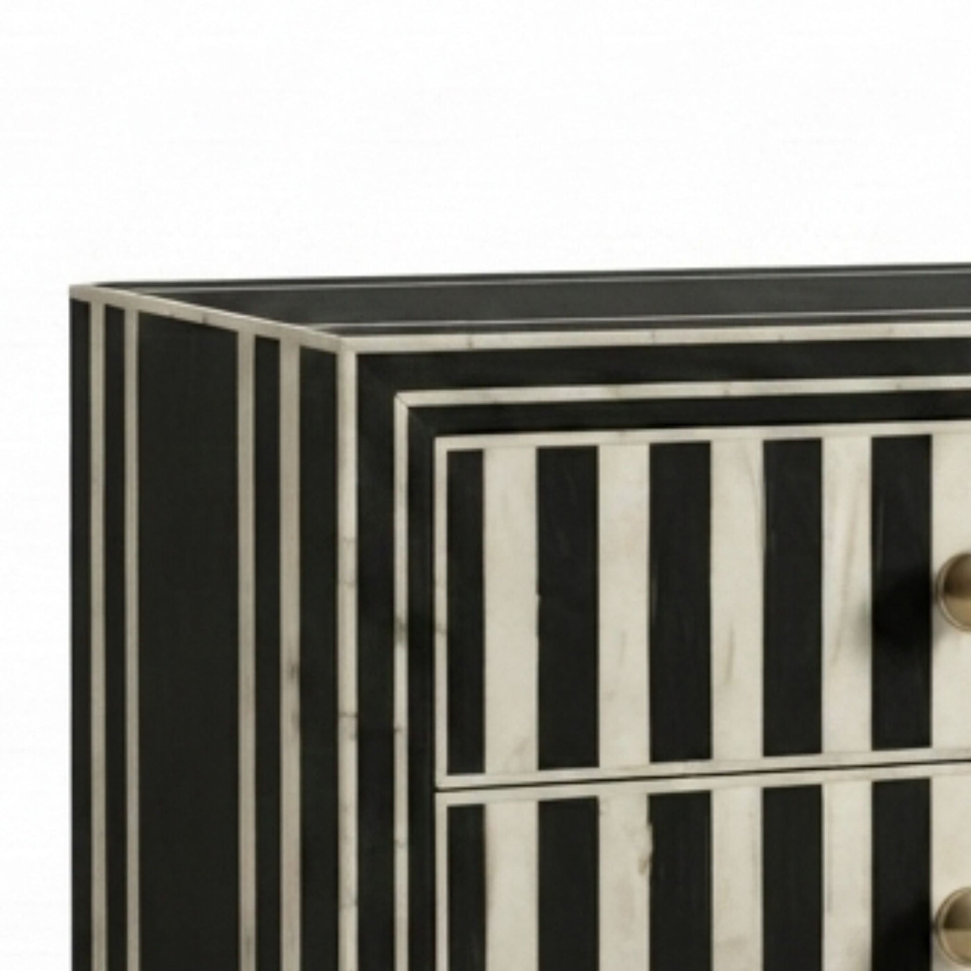 Close-up of a striped chest of drawers with black and white bone-inlay style panels and small round metallic knobs, shown against a plain white background.